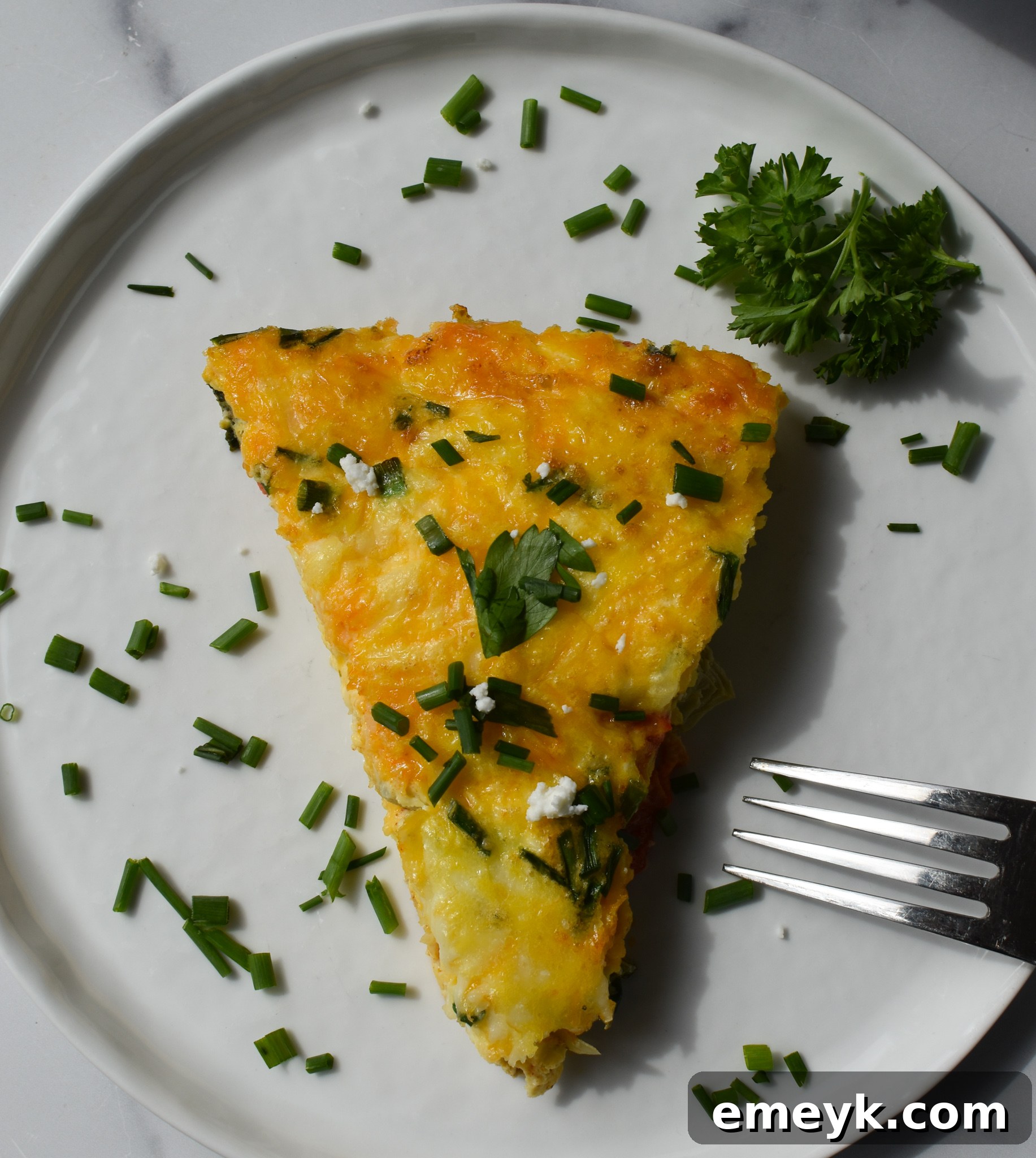 A slice of Mediterranean Vegetable Frittata on a white plate with a fork, showing its delicious layers.