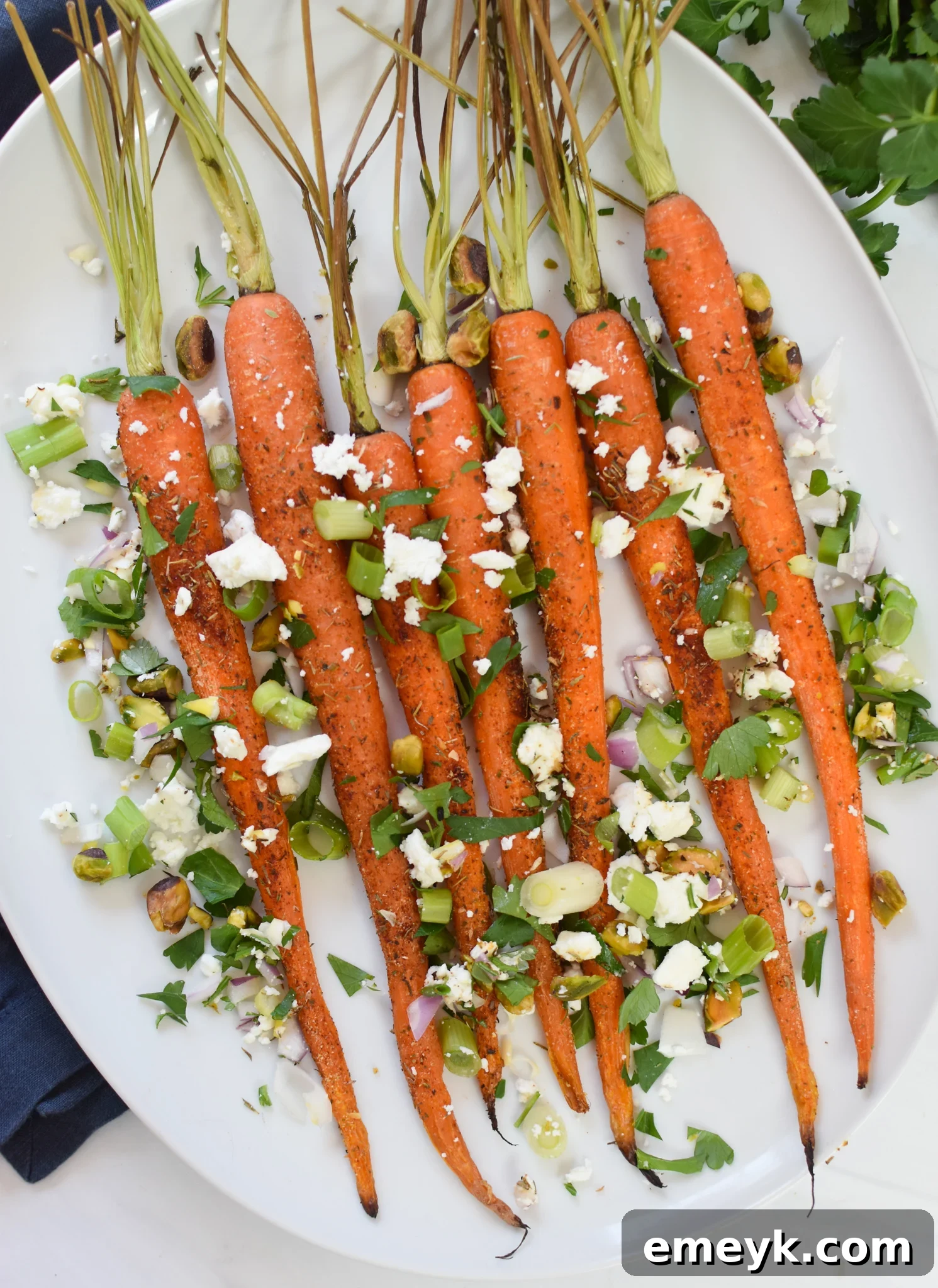 Roasted Carrots with Pistachios served on a elegant white platter, garnished with fresh herbs.