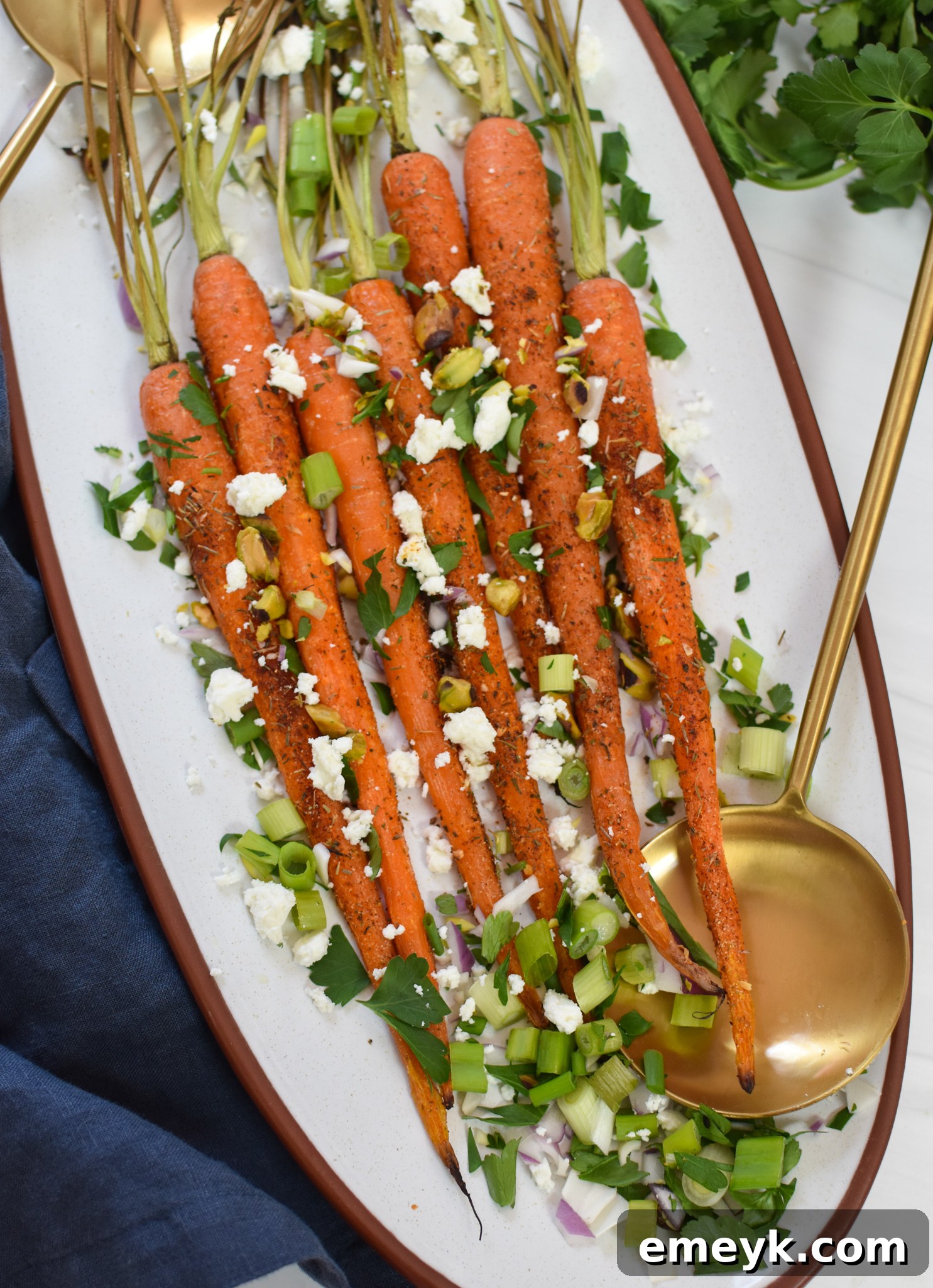 Roasted Carrots with Pistachios presented in a bowl with elegant gold serving spoons, ready to be enjoyed.