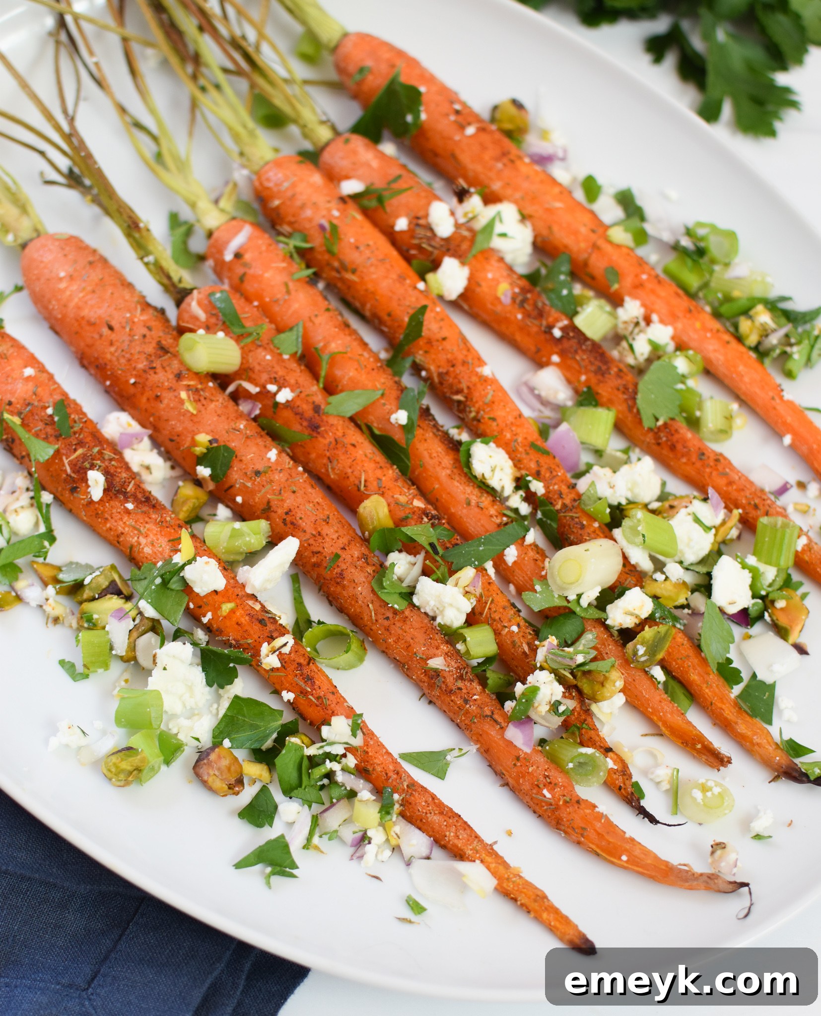 A bowl of Roasted Carrots with Pistachios, garnished with crumbled feta cheese and fresh herbs, ready to be served.