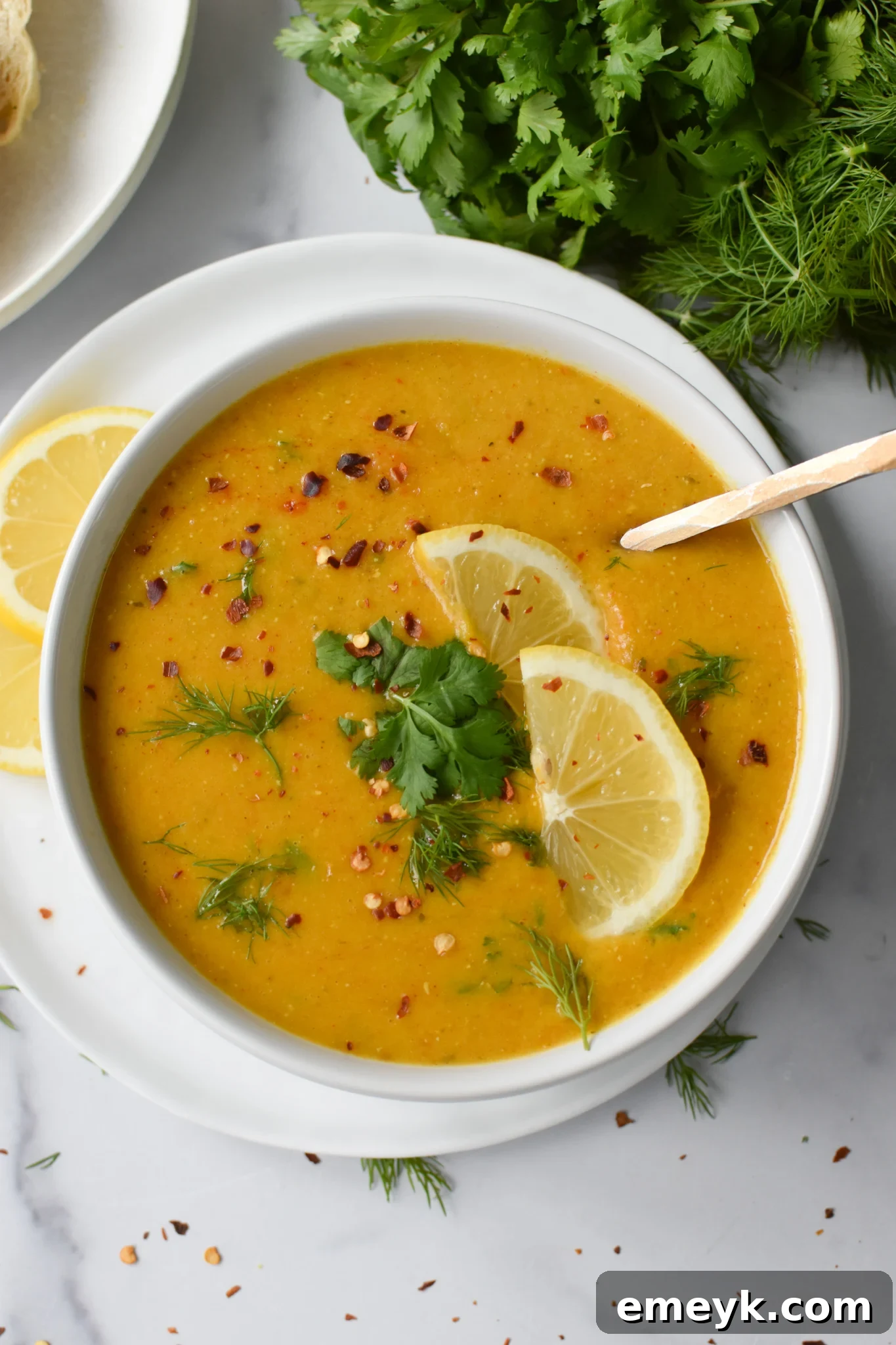 A spoon dipping into a bowl of Lemon Lentil Soup, showcasing its rich texture.