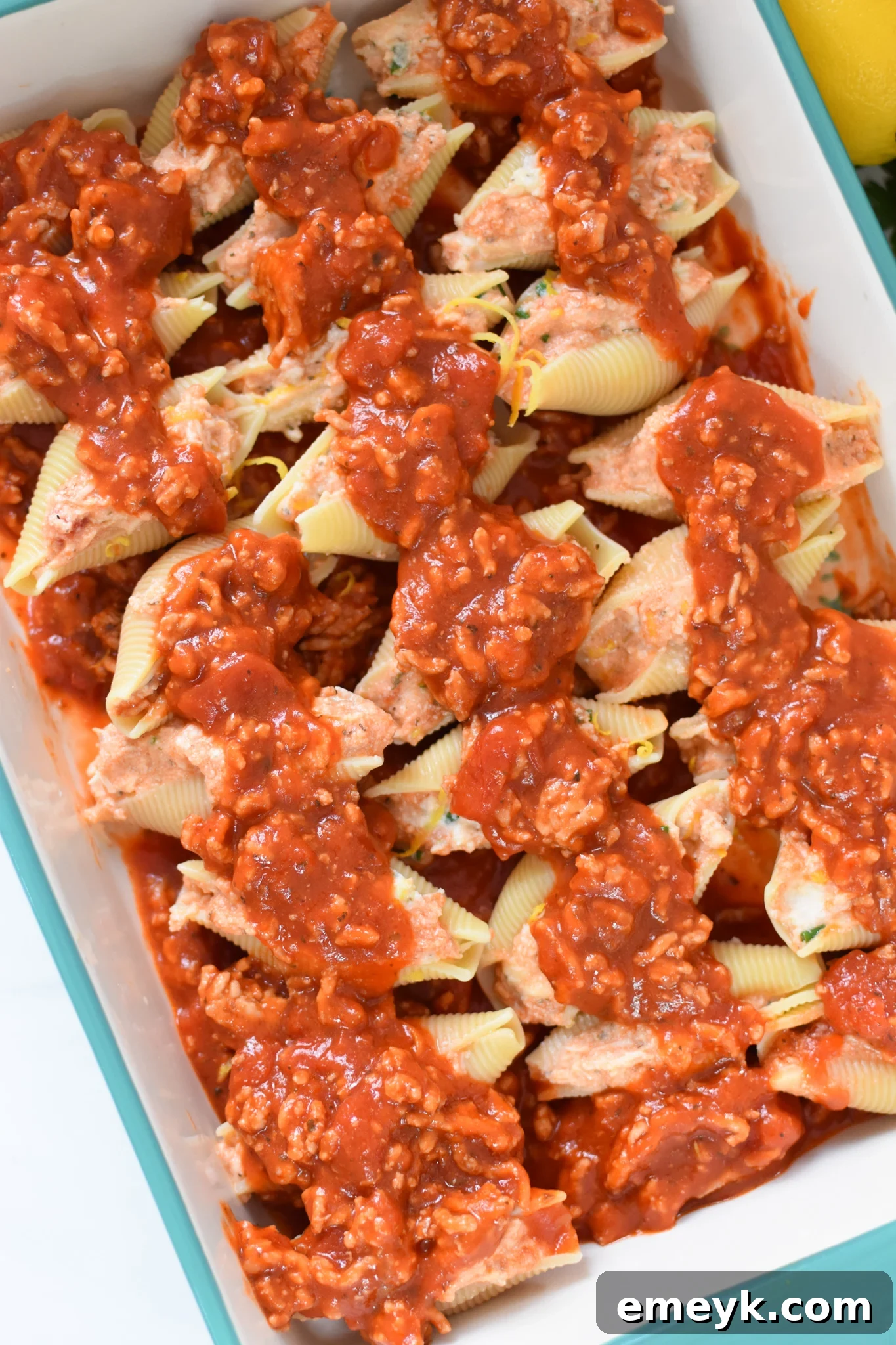 Veal Stuffed Shells arranged in a baking dish, covered with rich red sauce before baking.