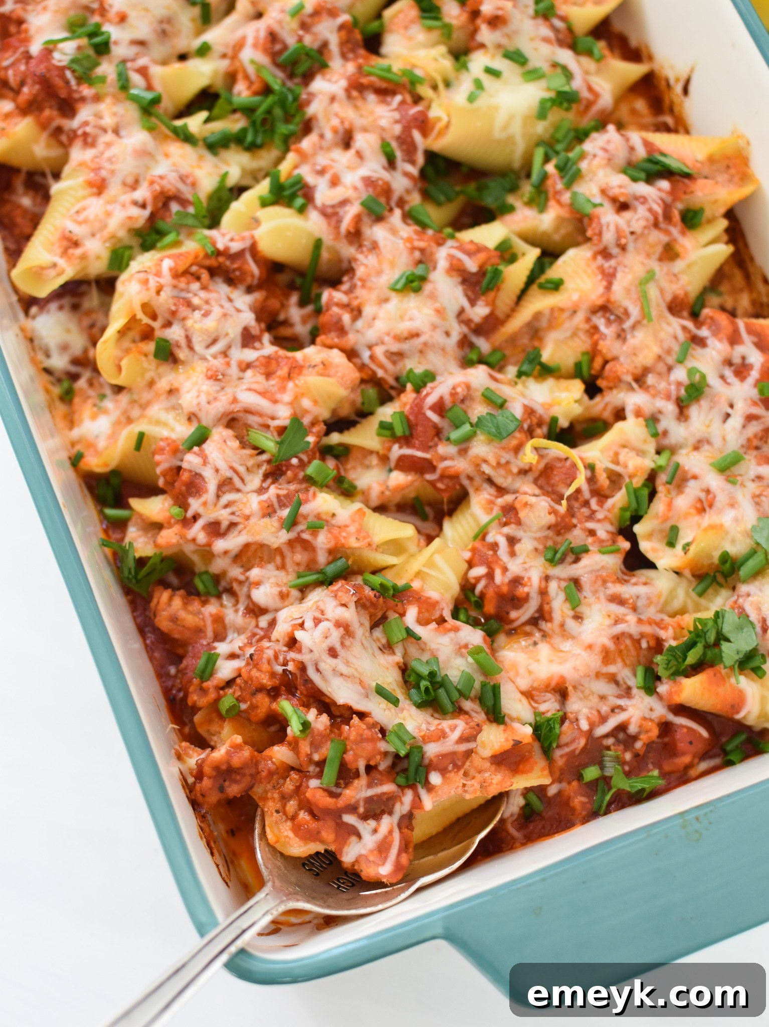 A top-down shot of baked Veal Stuffed Shells garnished with fresh chives, ready to be served.
