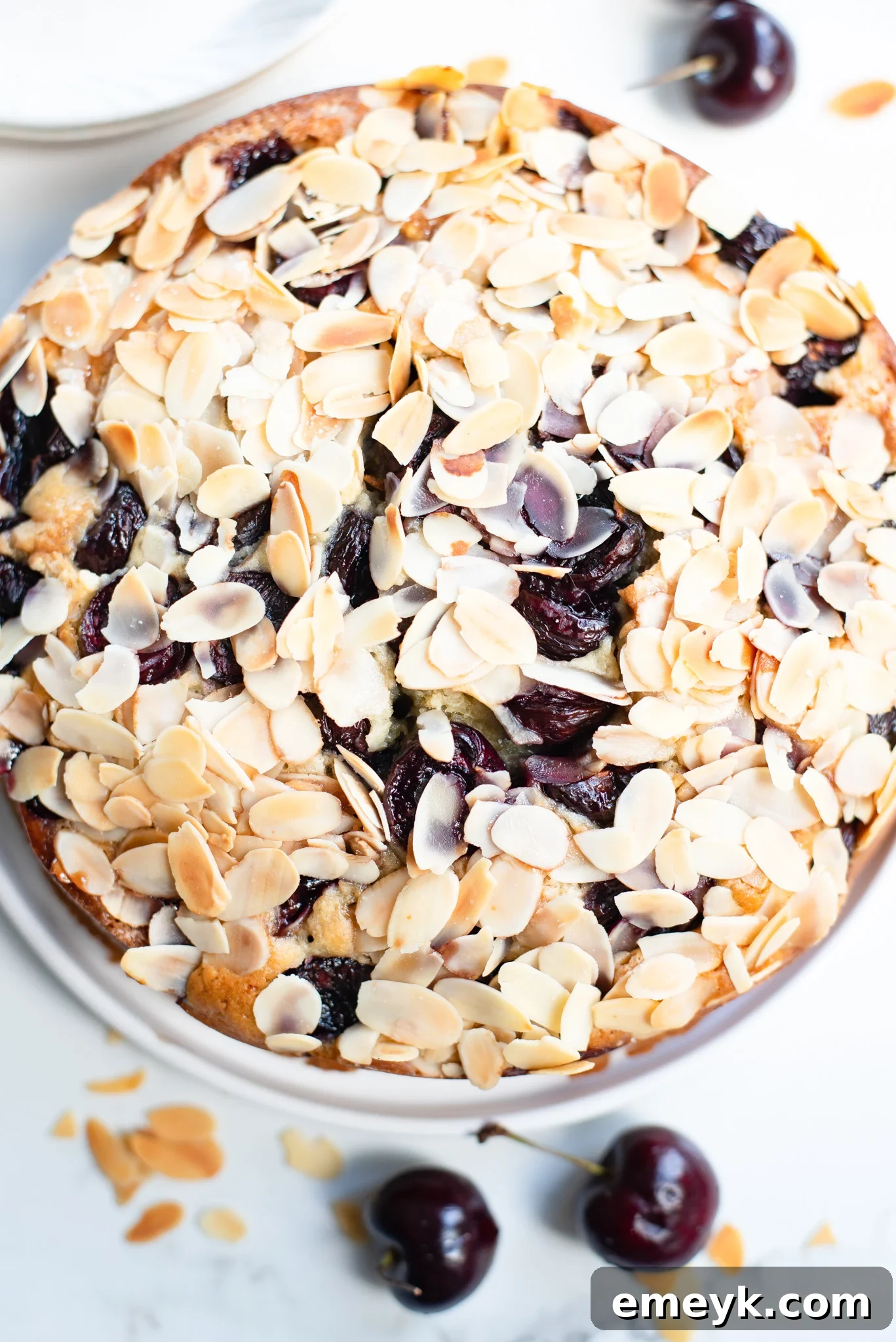 Decadent Cherry Almond Cake 2 A slice of Fresh Cherry Almond Cake on a white plate, showcasing its moist texture and vibrant cherry pieces.