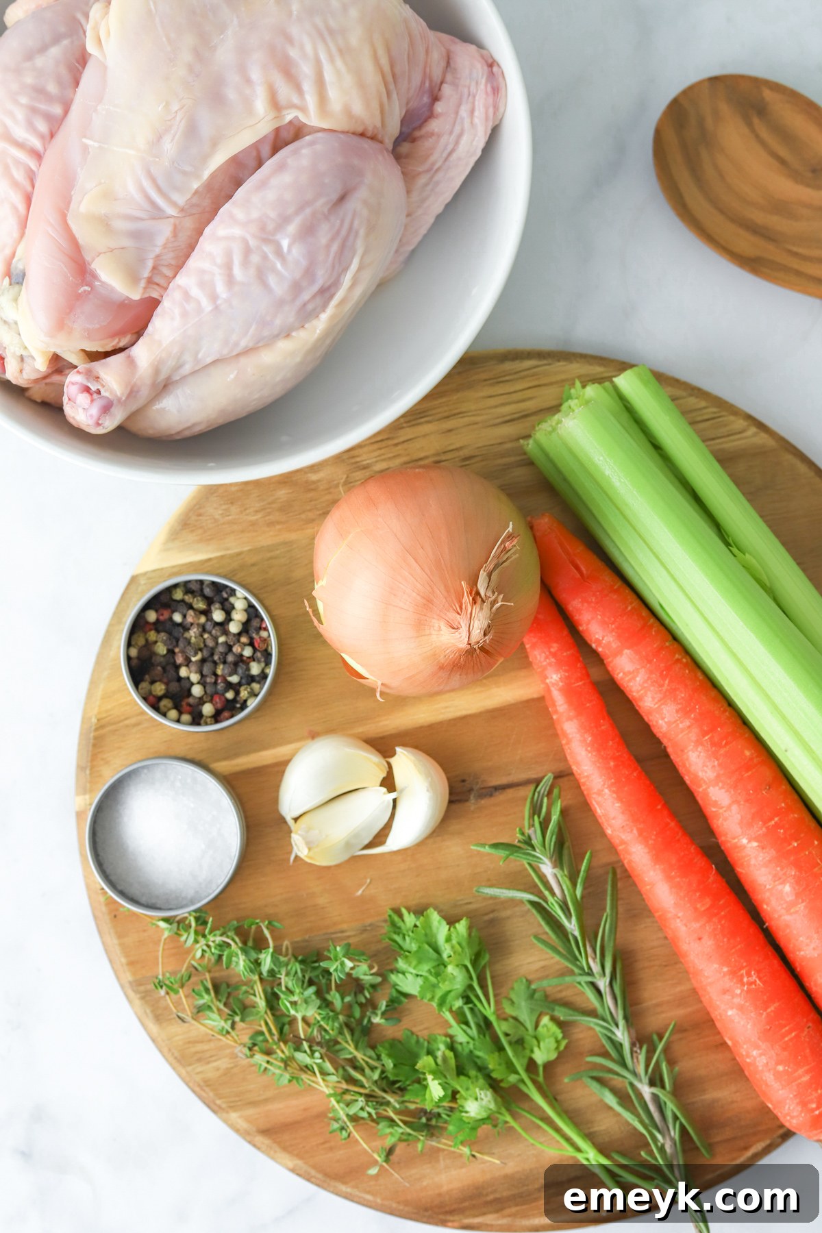 A vibrant selection of ingredients for homemade chicken broth, including a whole chicken, carrots, celery, onions, garlic, and fresh herbs.