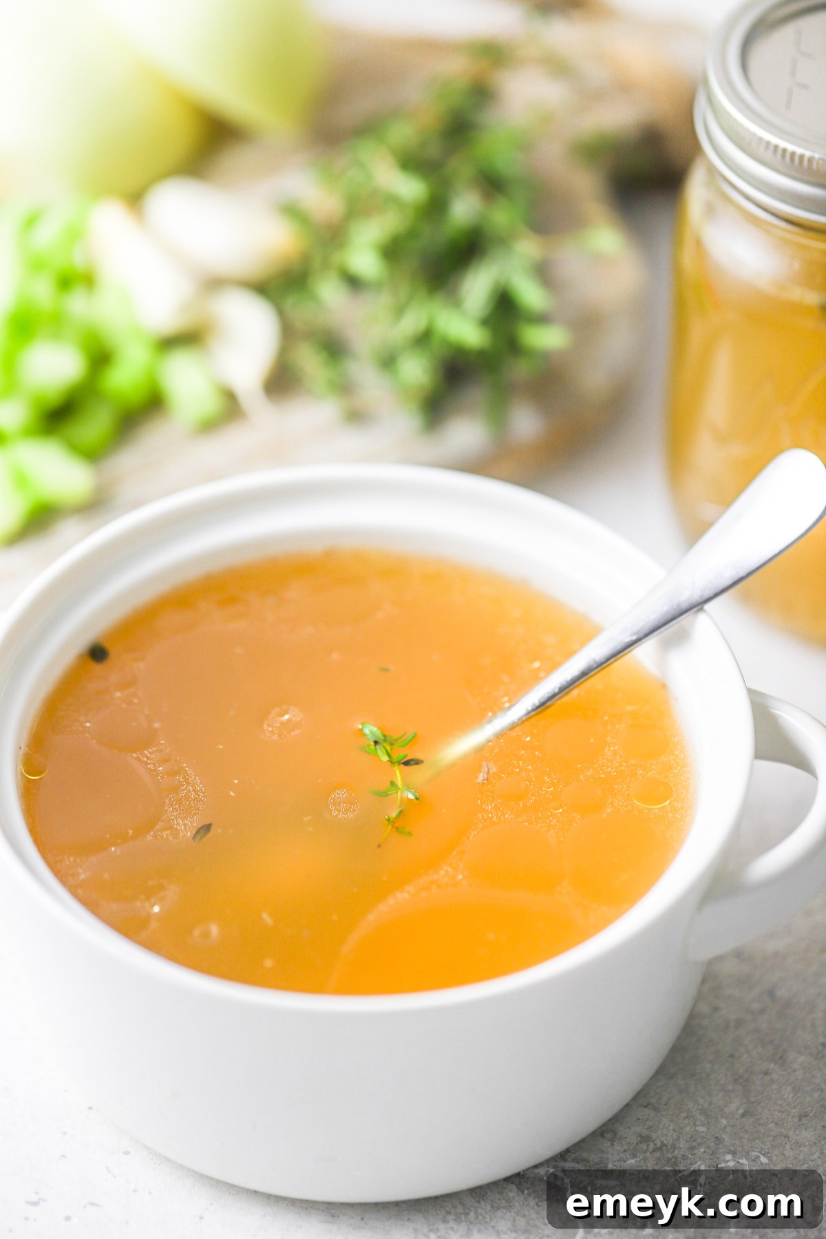 A steaming bowl of homemade chicken broth, garnished with fresh parsley.