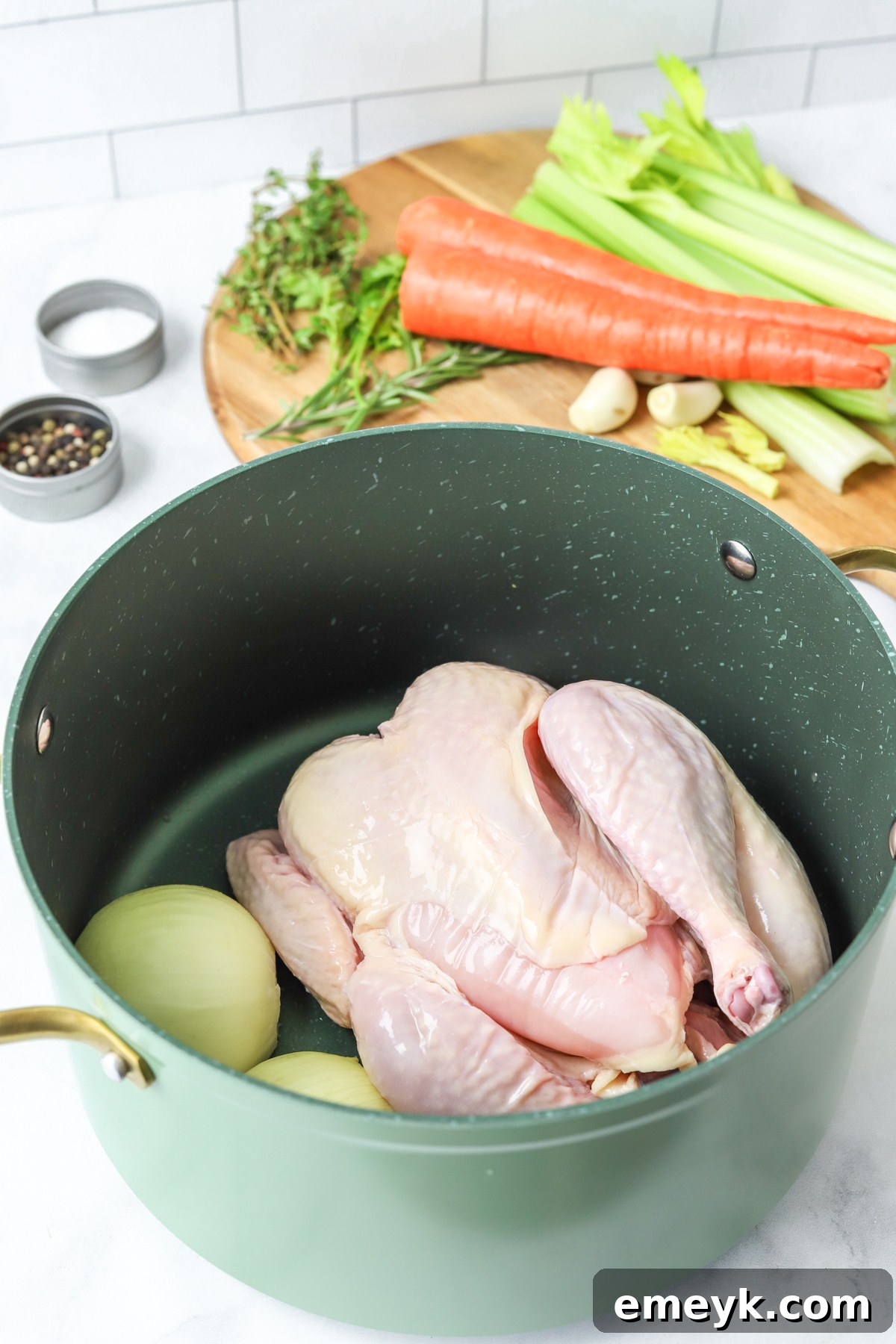 A whole chicken and vegetables browning in a large stockpot.