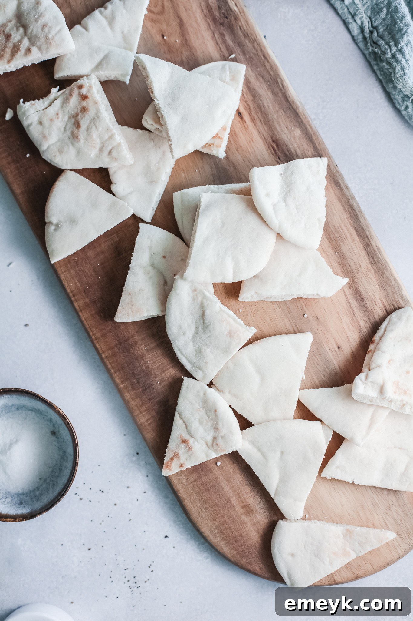 Pita bread being cut into triangles on a cutting board.