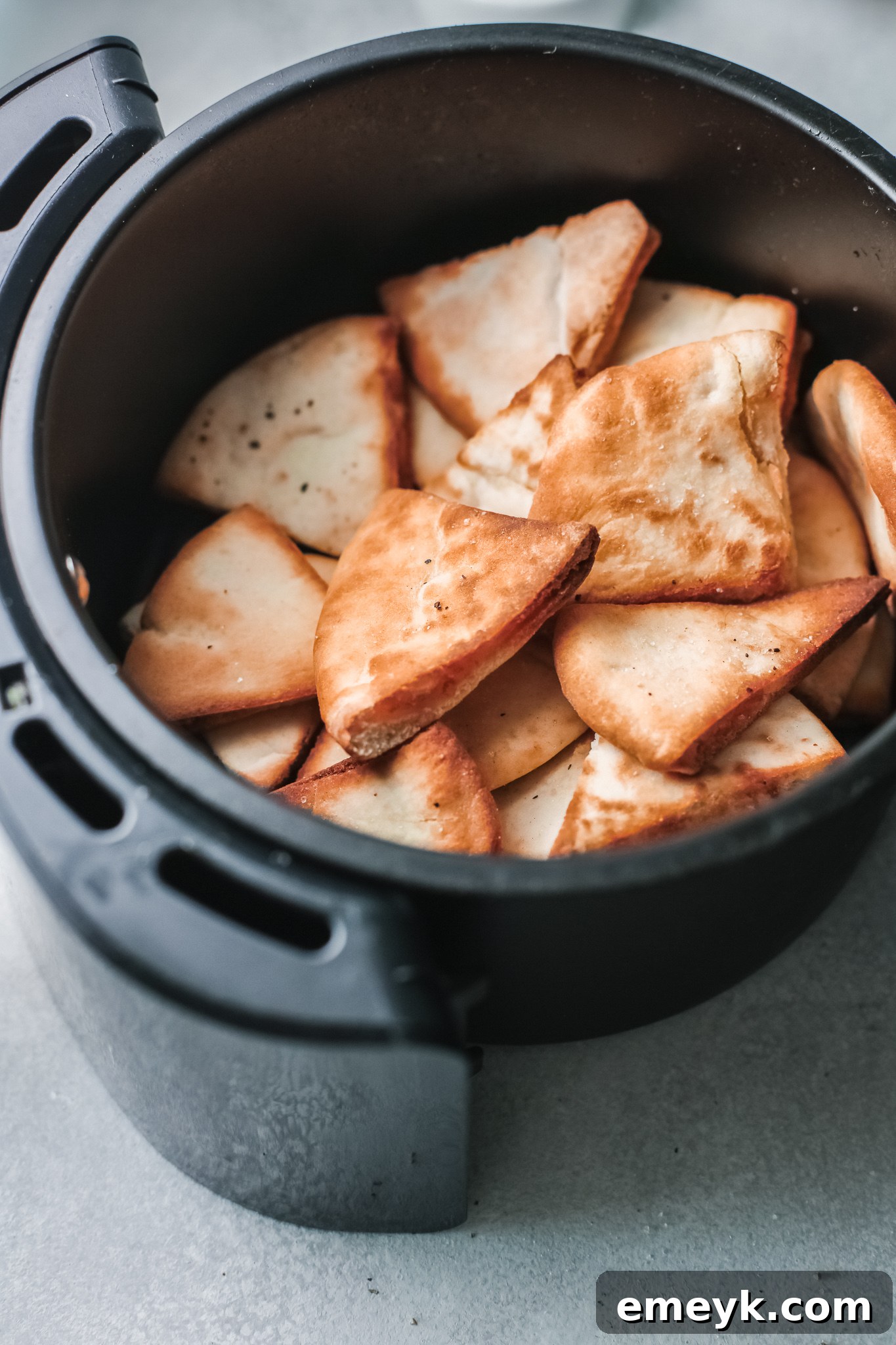 Crispy Air Fryer Pita Chips cooling in the air fryer basket.