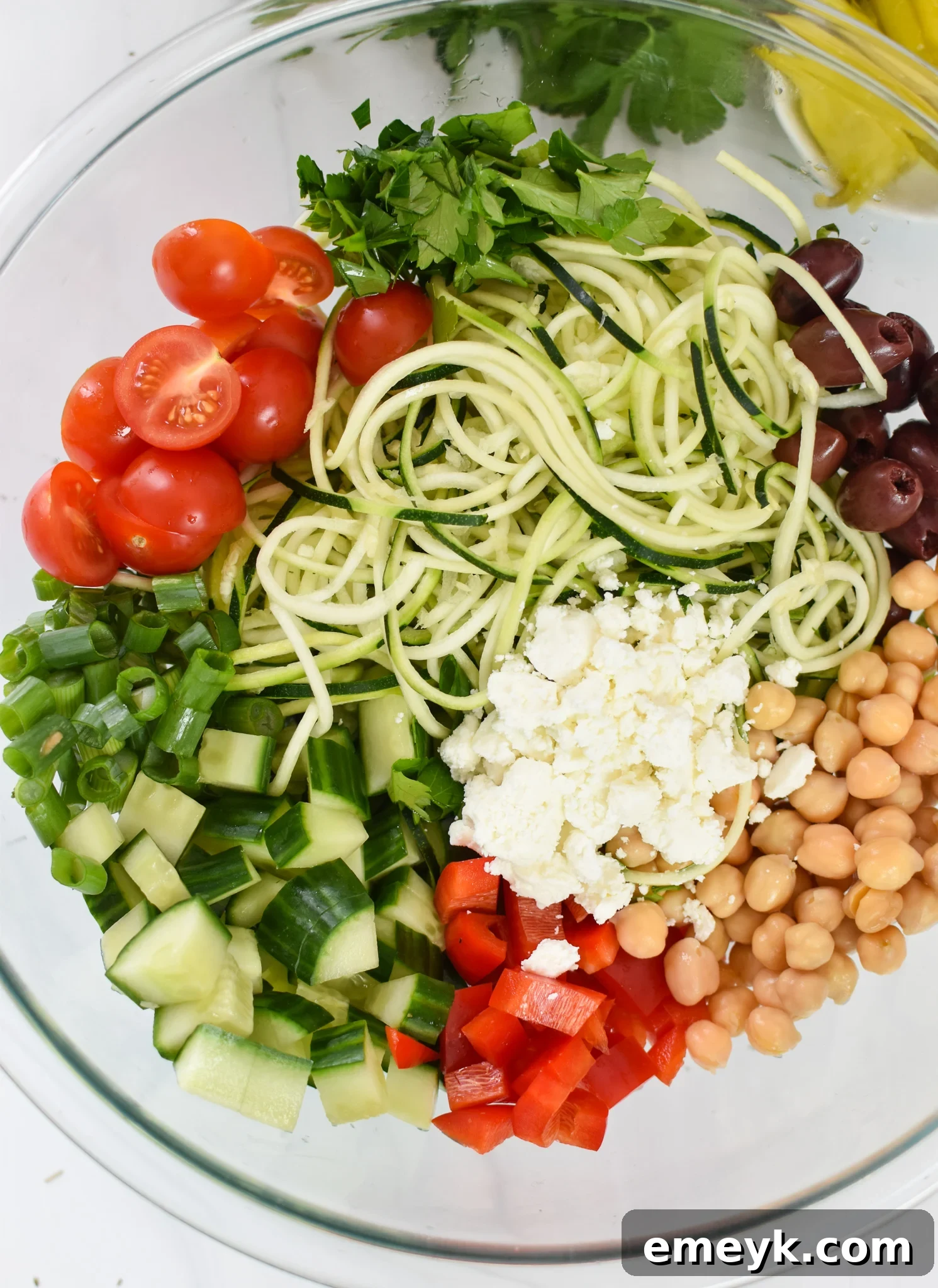 Zucchini and Pasta Mediterranean Medley 4 A close-up view of the prepared Mediterranean Zucchini Pasta Salad ingredients in a large glass bowl, ready for dressing.