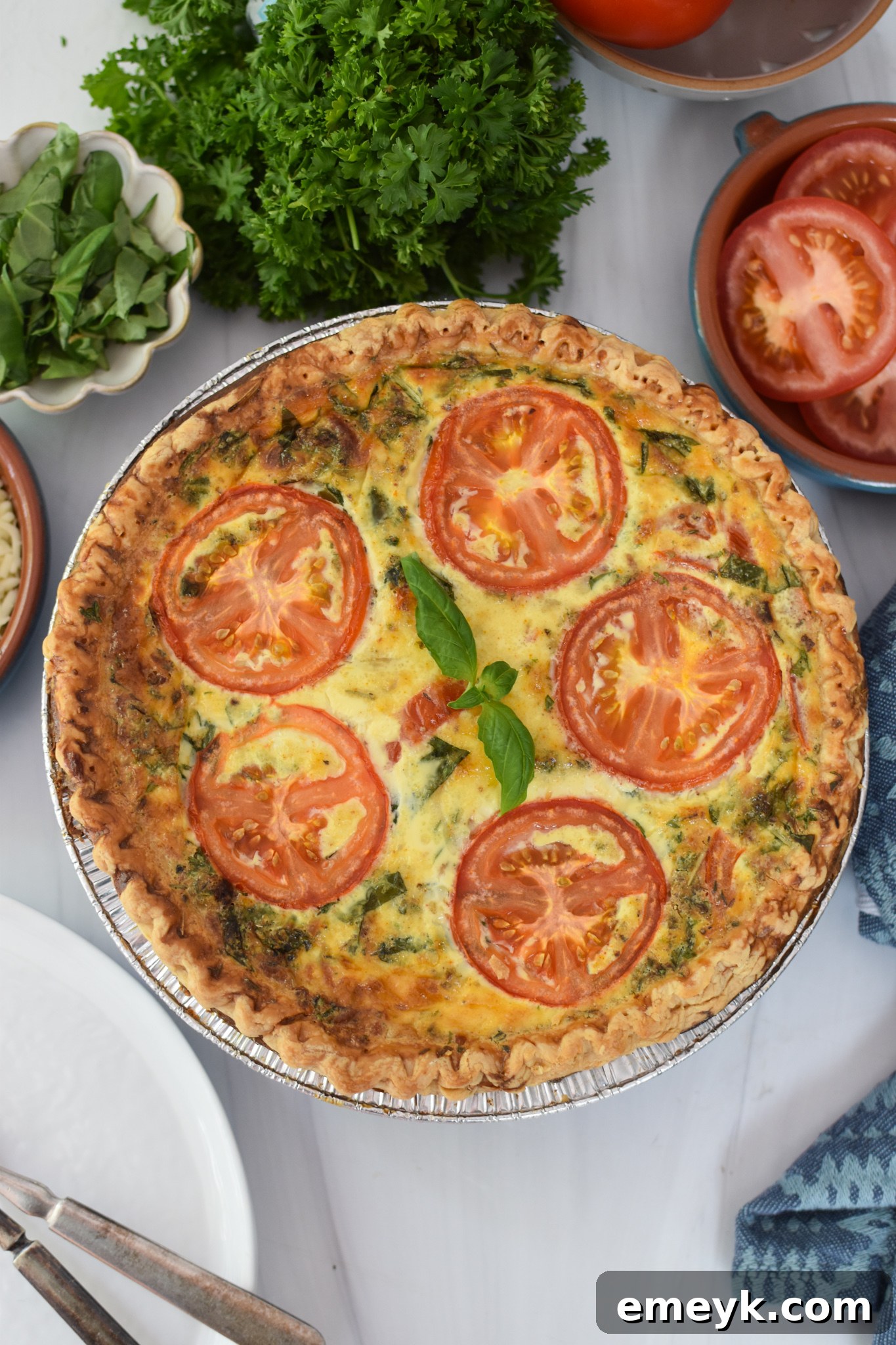 A slice of Caprese Quiche Lorraine with fresh basil garnish, highlighting the layers of tomato, mozzarella, and bacon.