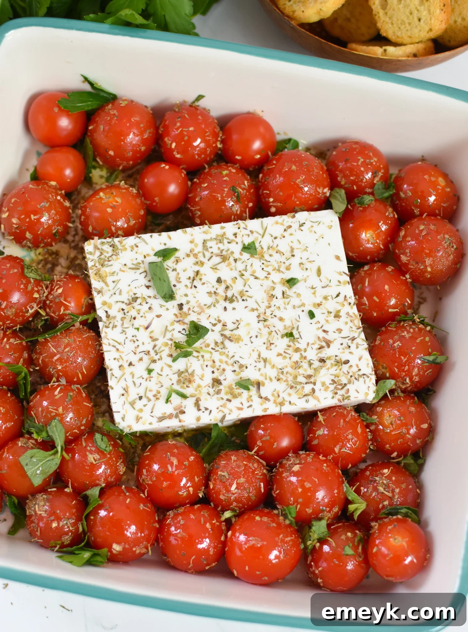 Effortless Baked Feta Delight 6 Block of feta cheese nestled among cherry tomatoes in a blue baking dish, ready for seasoning.