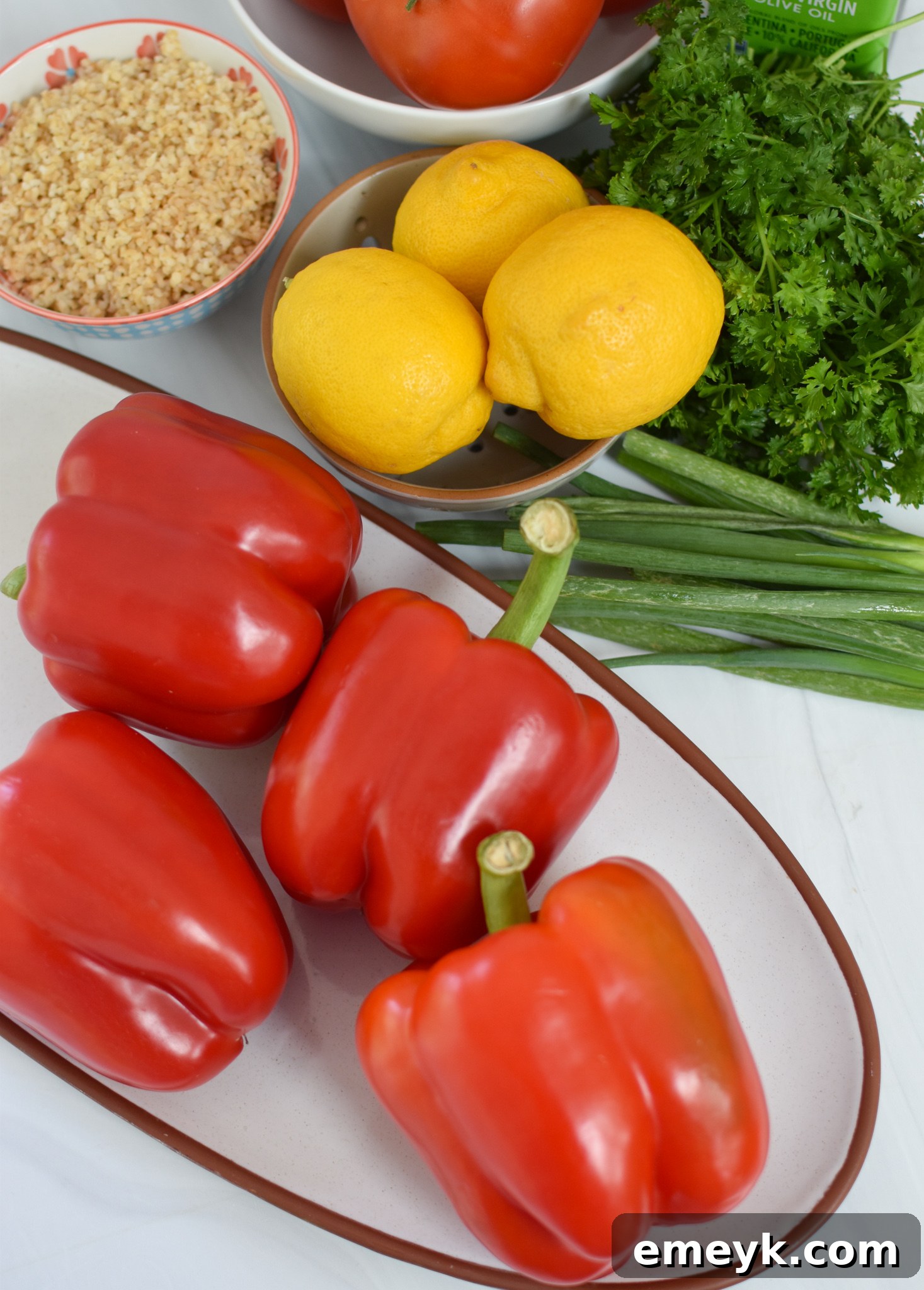 Collection of fresh ingredients for Vegan Tabbouleh Stuffed Peppers, including parsley, tomatoes, mint, bulgur, and green onions.