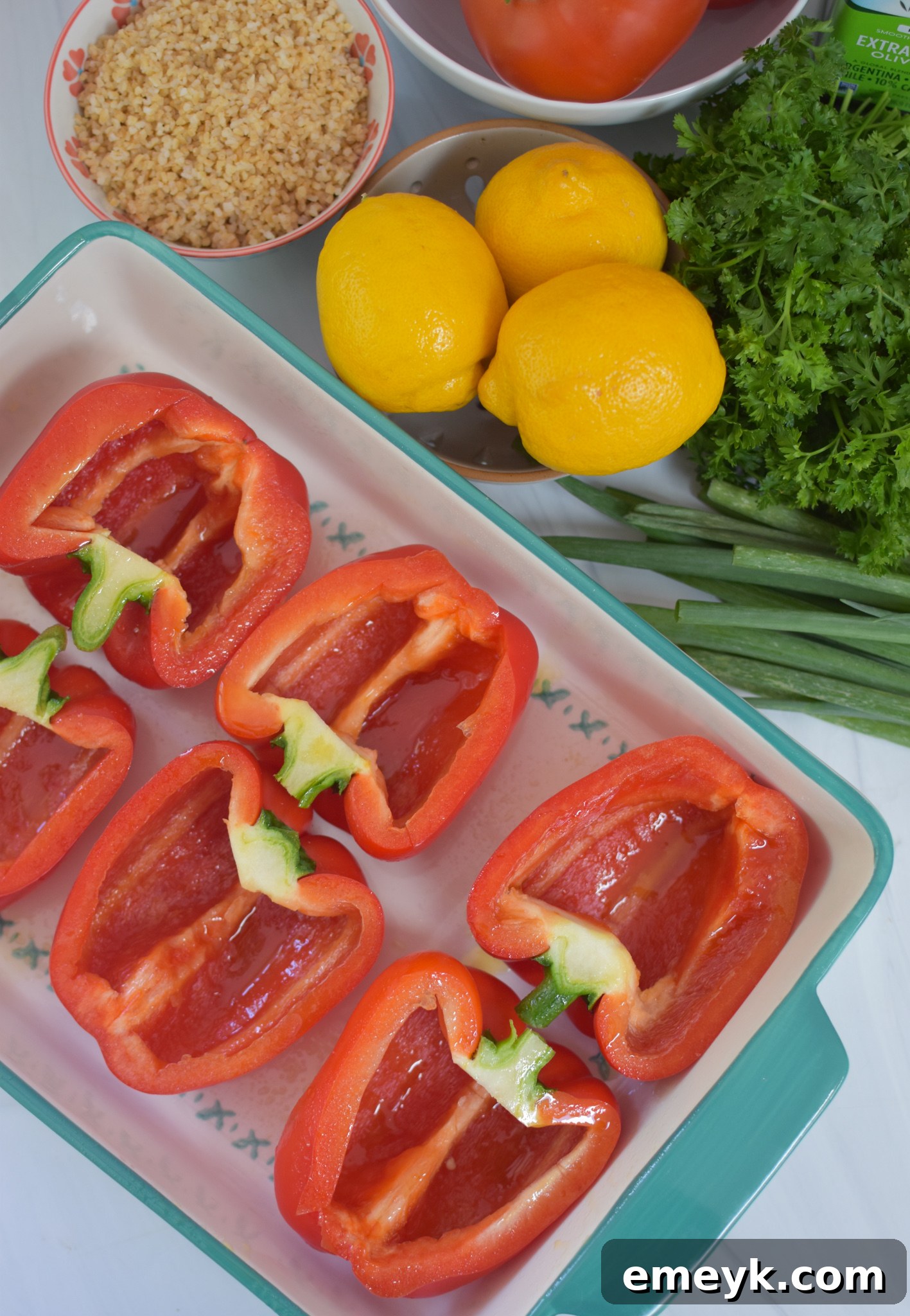 Bell peppers par-baked in a dish, glistening and softened, waiting for the tabbouleh filling in a Vegan Stuffed Peppers Recipe.