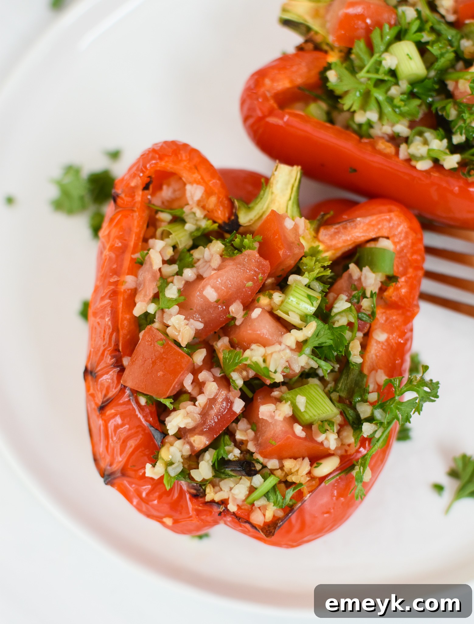 Finished Vegan Tabbouleh Stuffed Peppers, garnished with fresh tabbouleh, on a serving board.