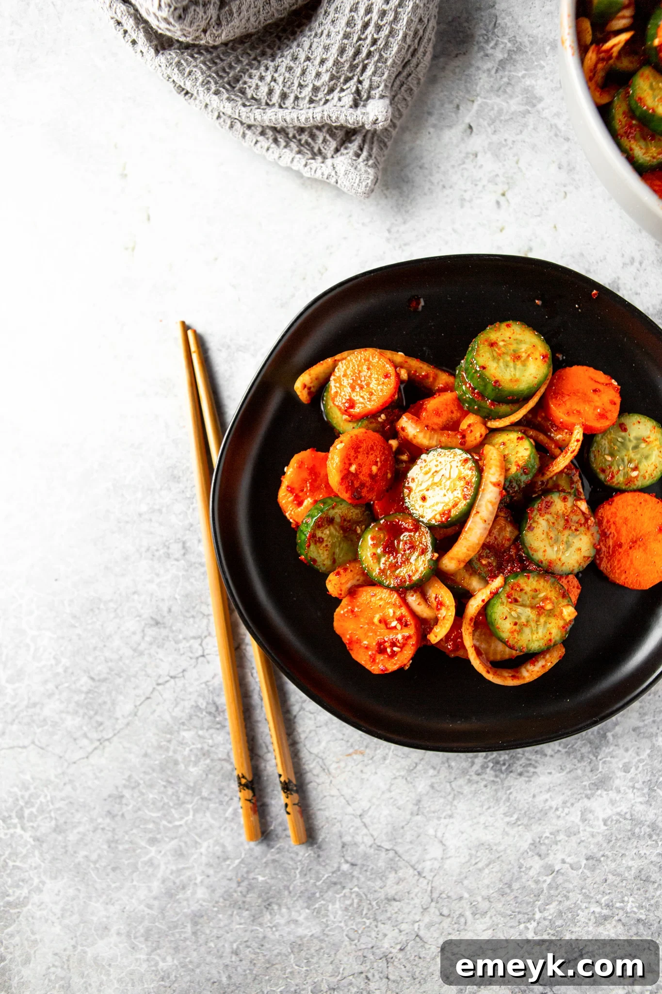 A small bowl of Quick Korean Cucumber Kimchi, with chopsticks resting, inviting the viewer to enjoy this savory and crisp side dish.