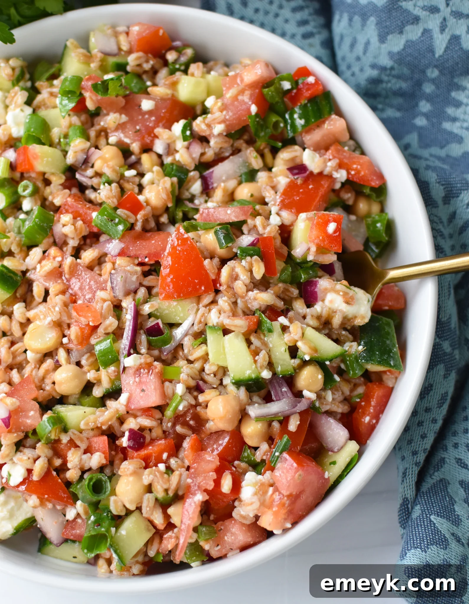 A serving of Mediterranean Farro Salad in a bowl with a gold spoon, ready to enjoy.