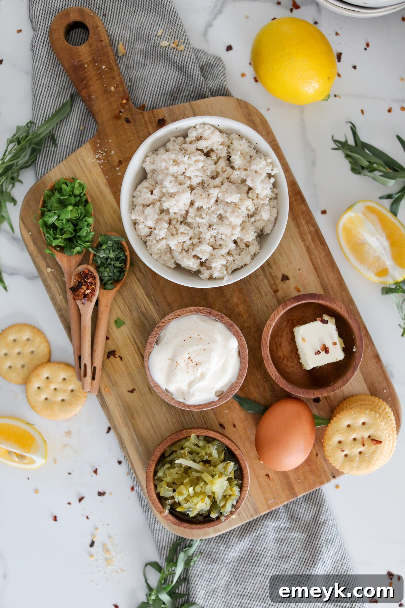 A collection of fresh ingredients laid out for an easy crab cake recipe, including lump crab meat, green onions, lemon, and spices.
