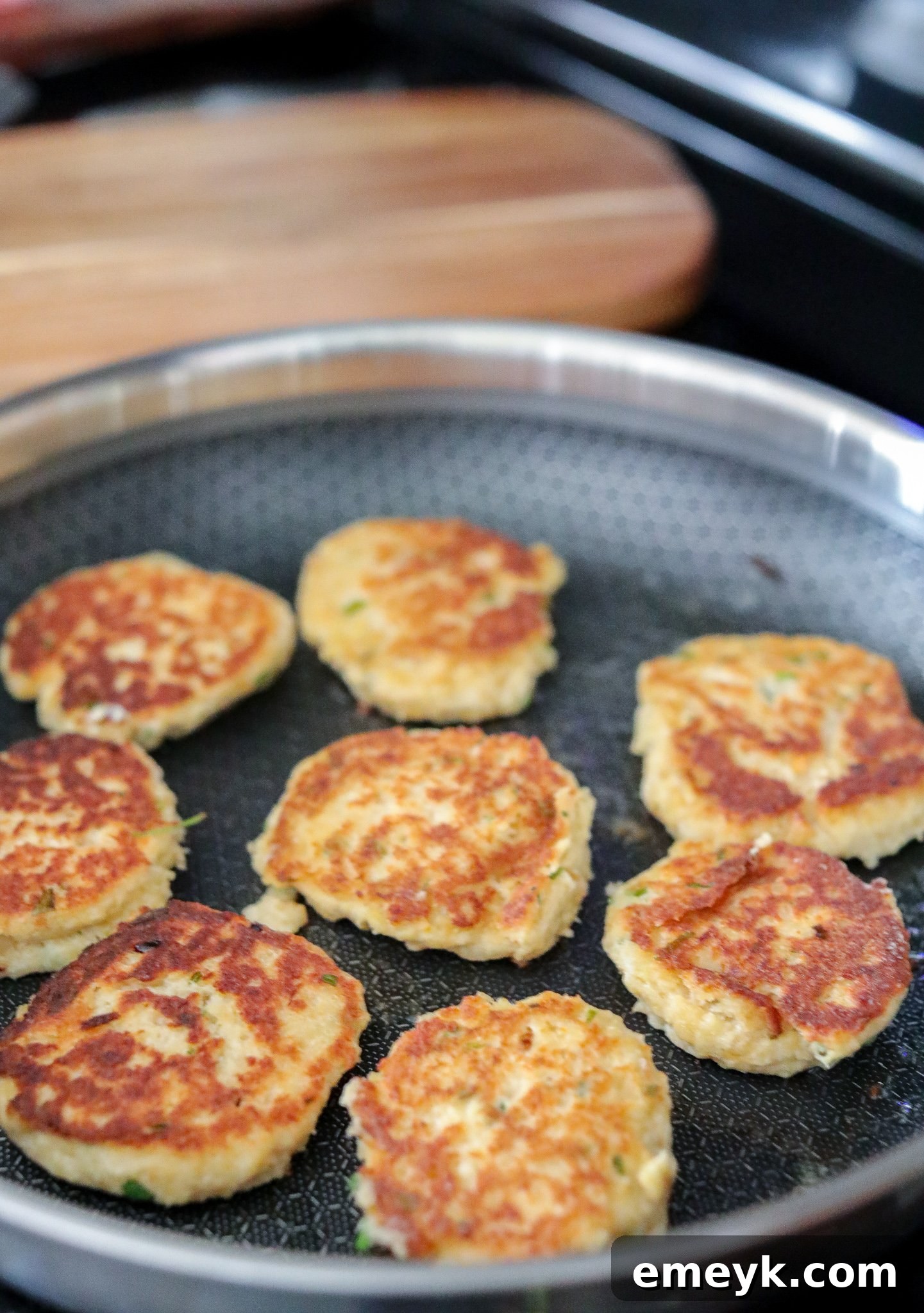 Easy crab cakes sizzling in a hot skillet, developing a golden brown crust.