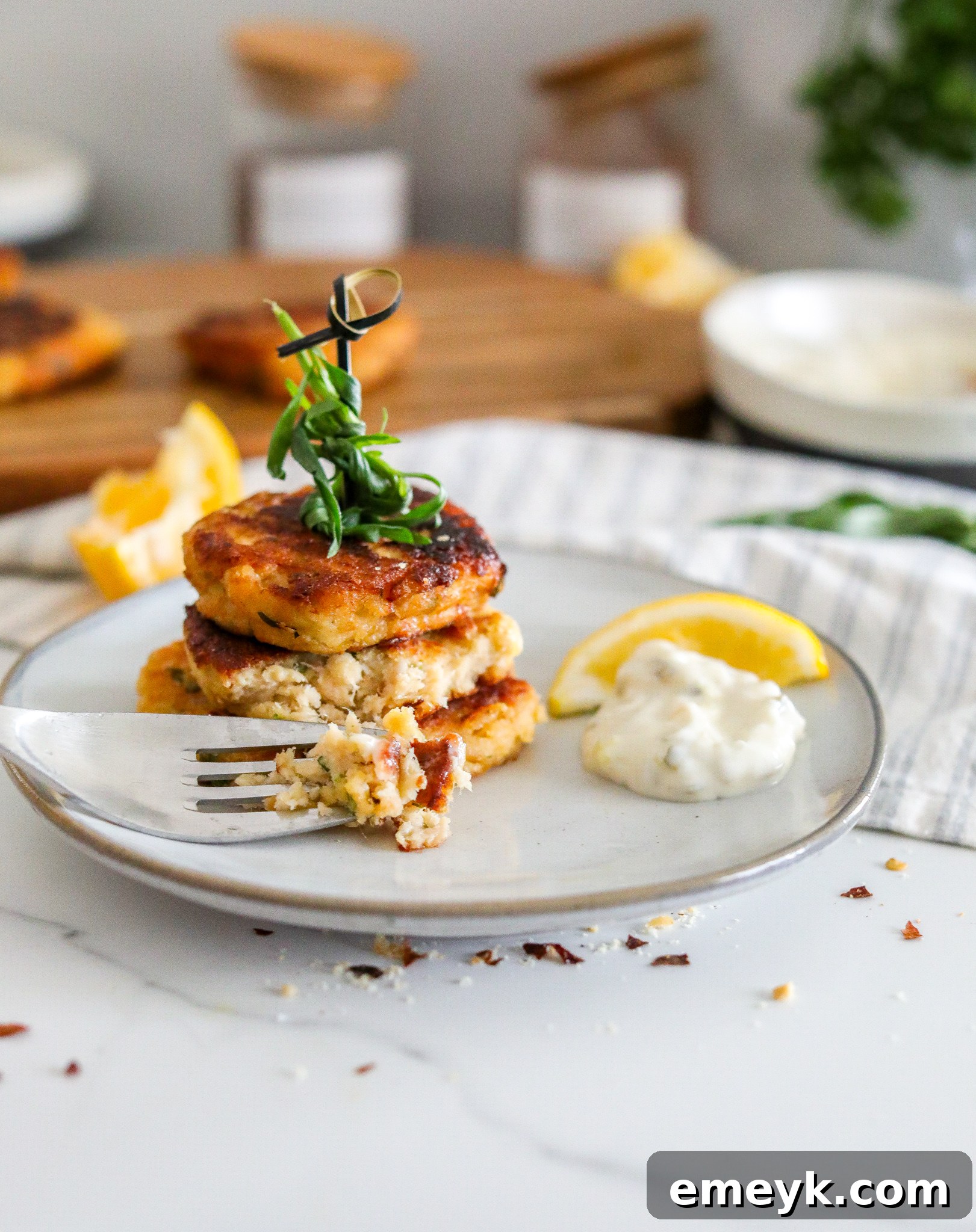 A perfectly cooked easy crab cake on a white plate, served with a dollop of tartar sauce and a lemon wedge.