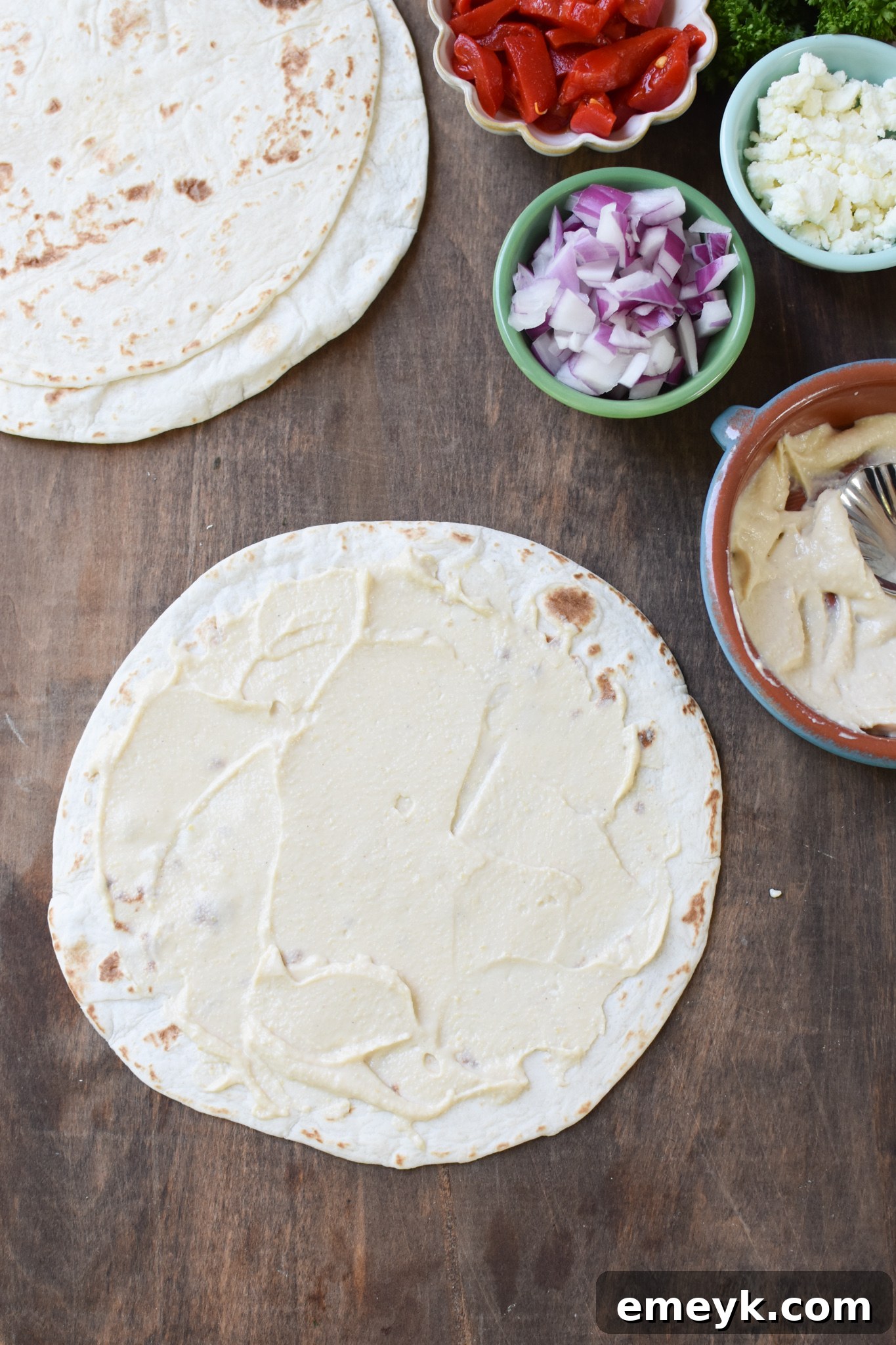 A tortilla with a generous layer of hummus spread evenly across its surface.