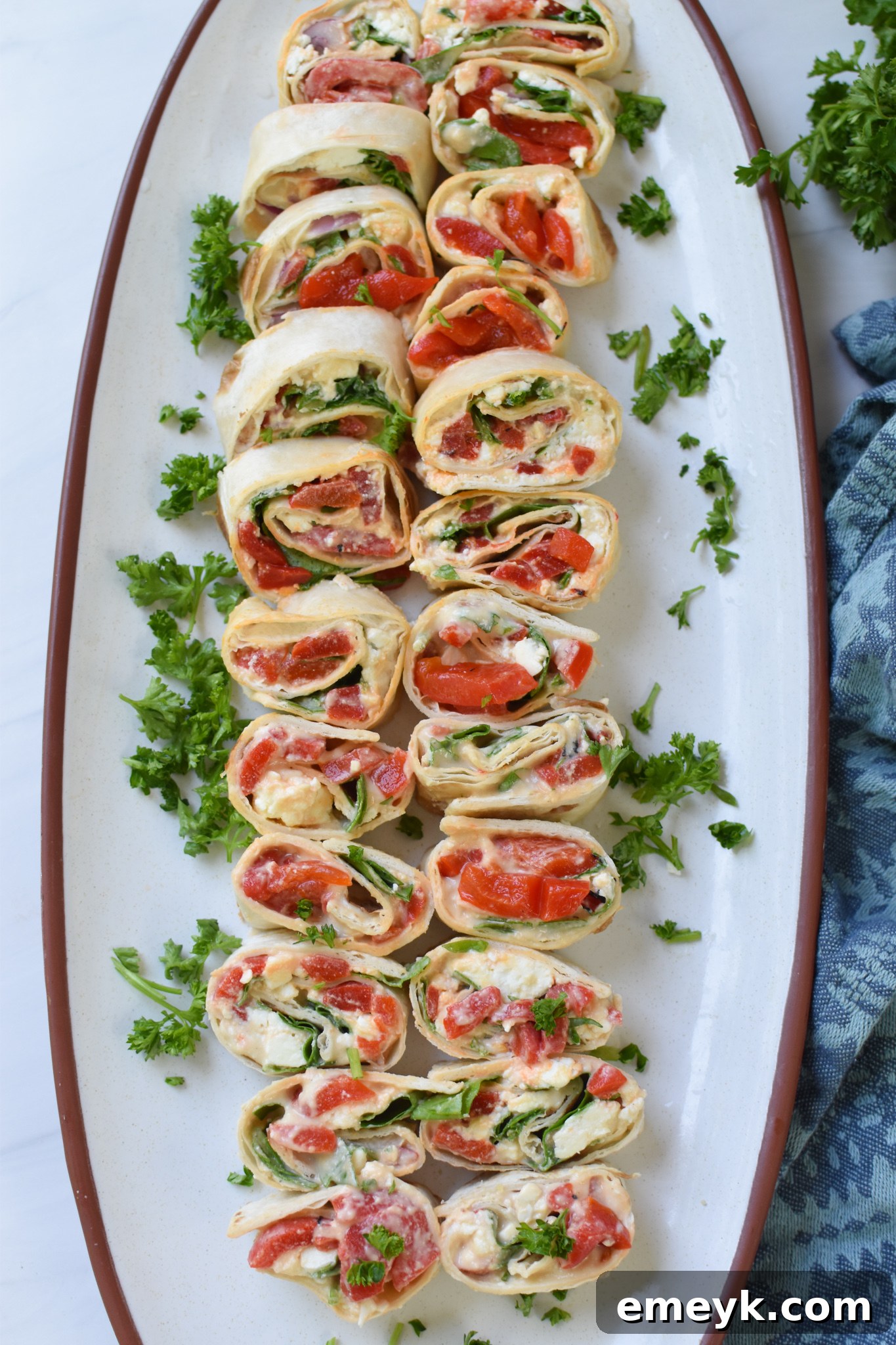 A stack of Mediterranean Pinwheels served on a white plate with a blue napkin, highlighting their inviting appearance.