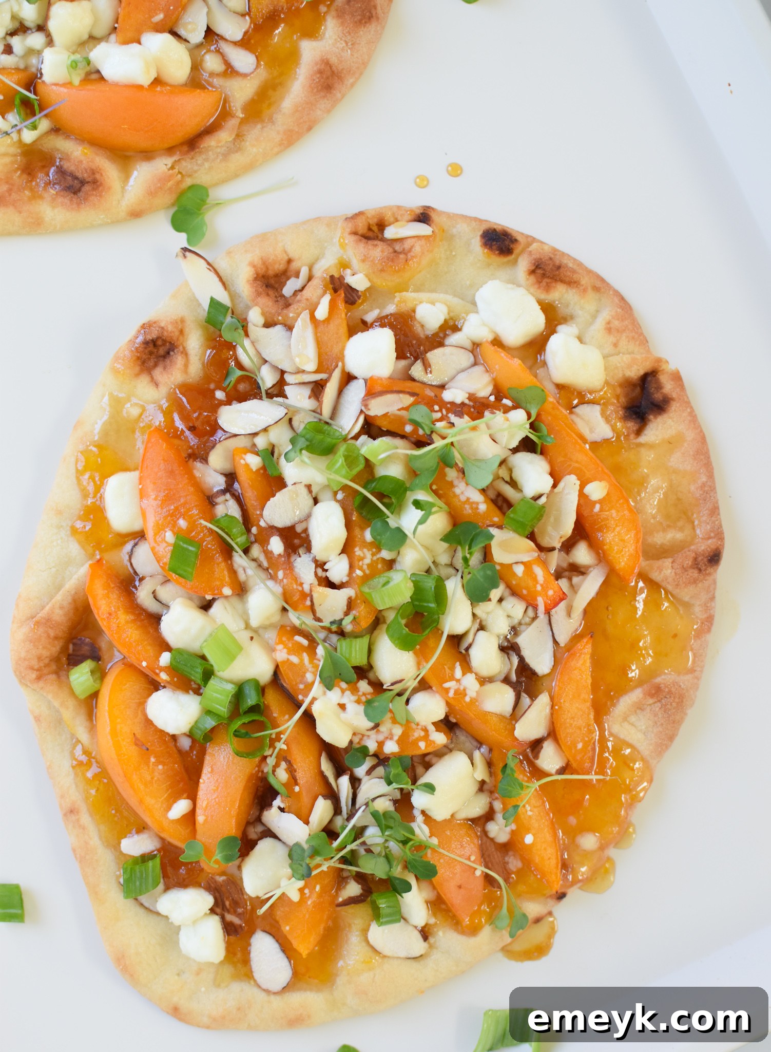 Golden Apricot & Chèvre Pizza 7 Goat Cheese Apricot Pizza on a white plate with a fork, ready to be eaten.