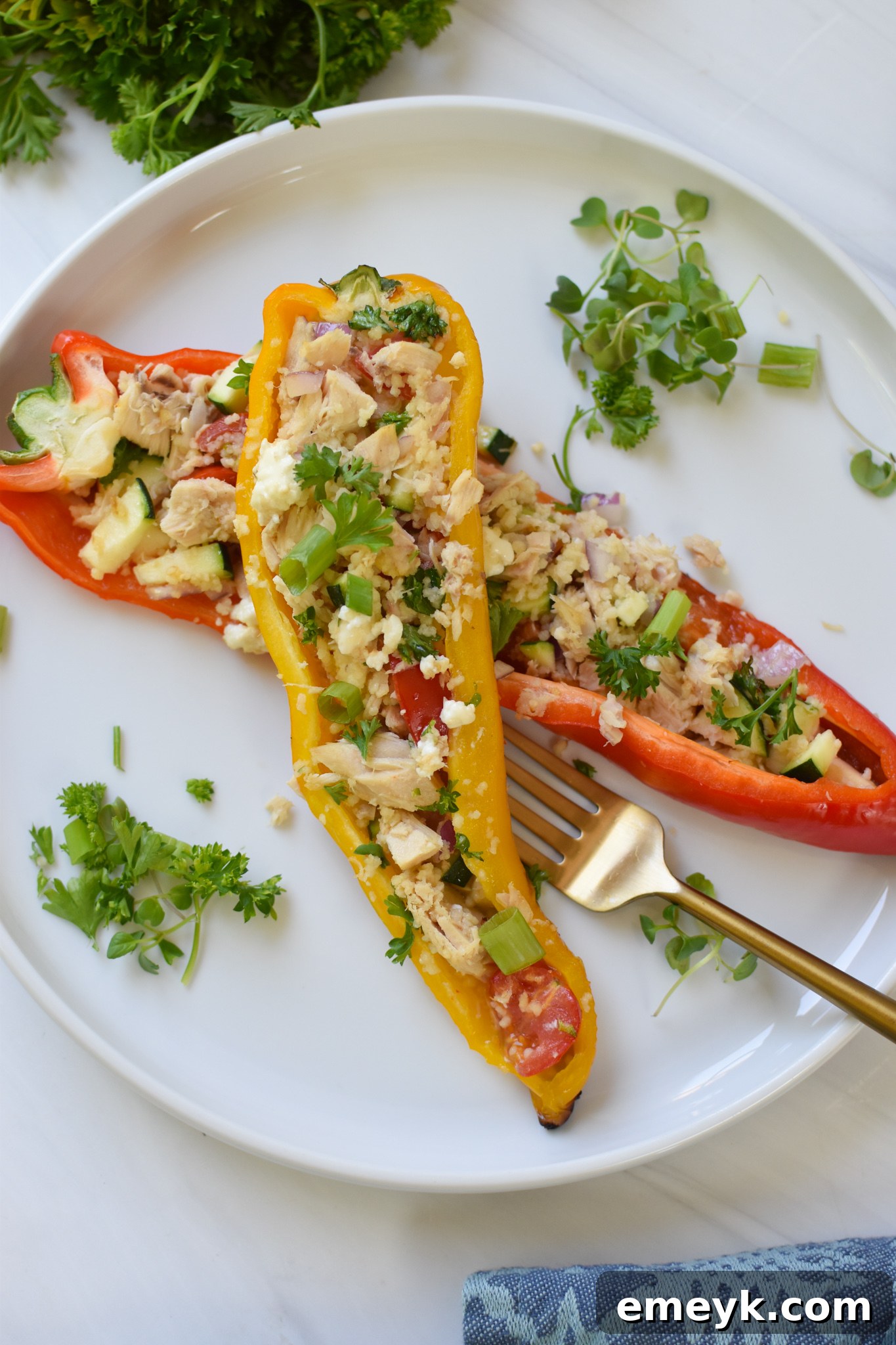 A close-up of Mediterranean Tuna Couscous Stuffed Peppers with a gold fork, showing the vibrant filling.