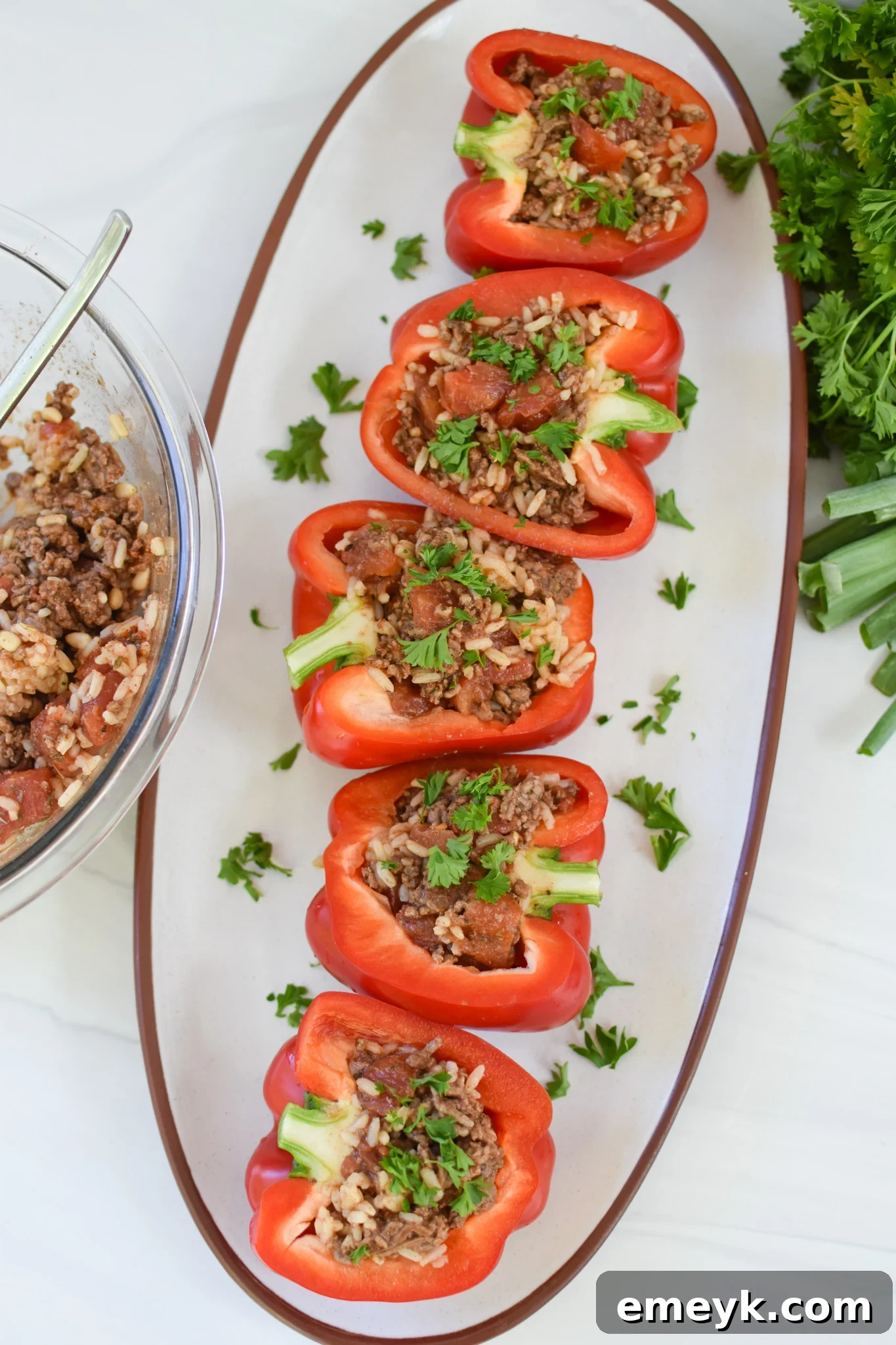 Hearty Mediterranean Beef Stuffed Peppers 11 Two Mediterranean Ground Beef Stuffed Peppers on a white plate, garnished with fresh herbs.