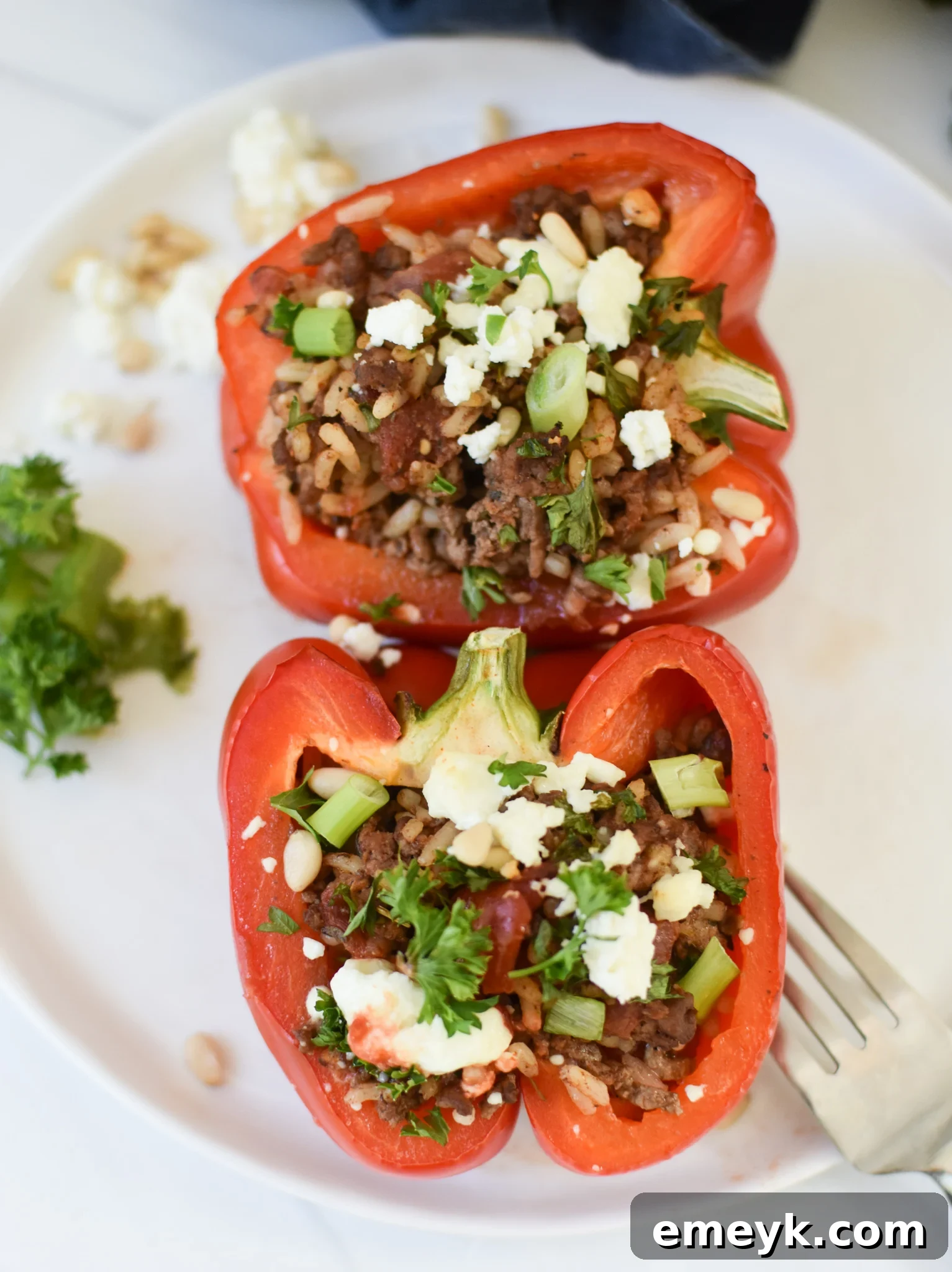 Hearty Mediterranean Beef Stuffed Peppers 6 A single Mediterranean Ground Beef Stuffed Pepper on a white plate, garnished with fresh herbs.