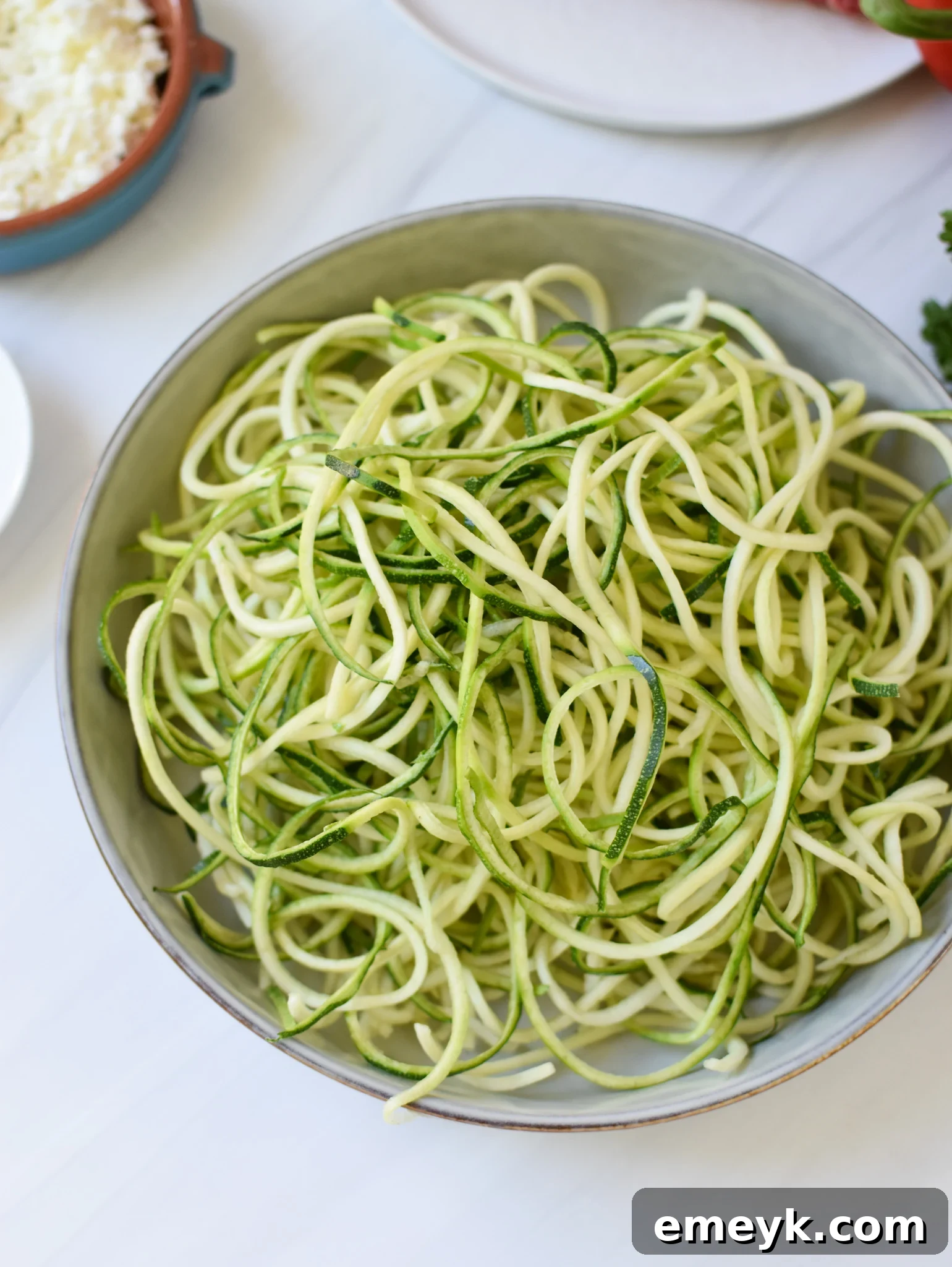 Freshly spiralized zucchini noodles in a white bowl, a key ingredient for the Mediterranean Ground Beef Zucchini Skillet.