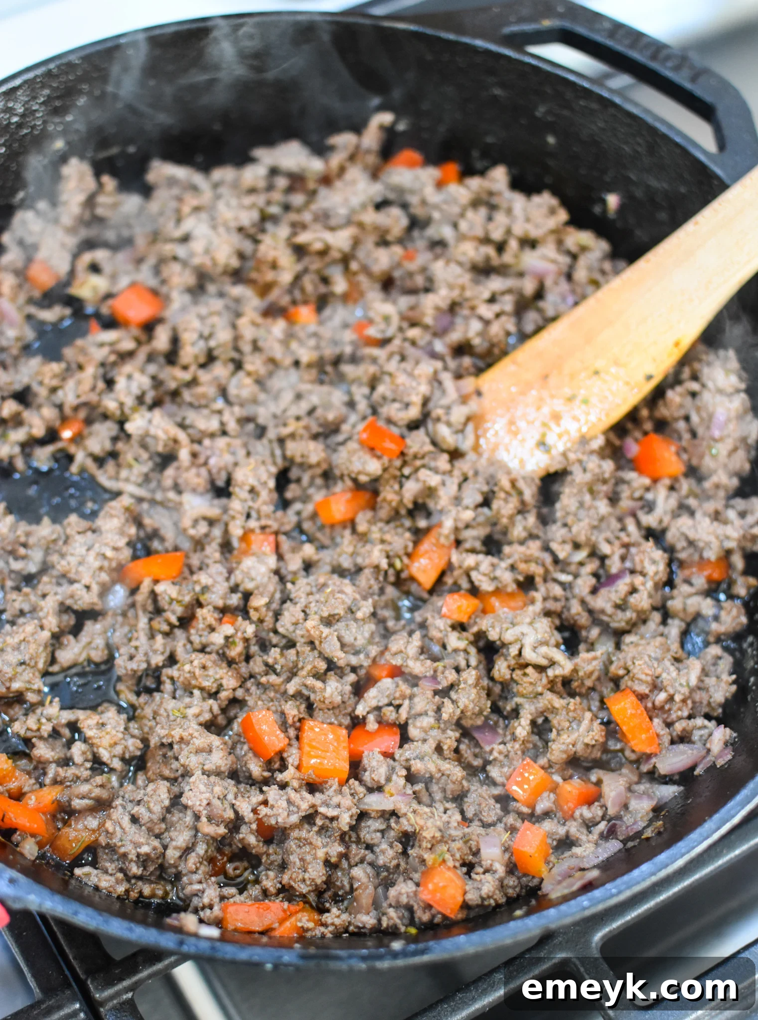 Ground beef cooking in a skillet with a blend of Mediterranean spices, releasing an aromatic fragrance.