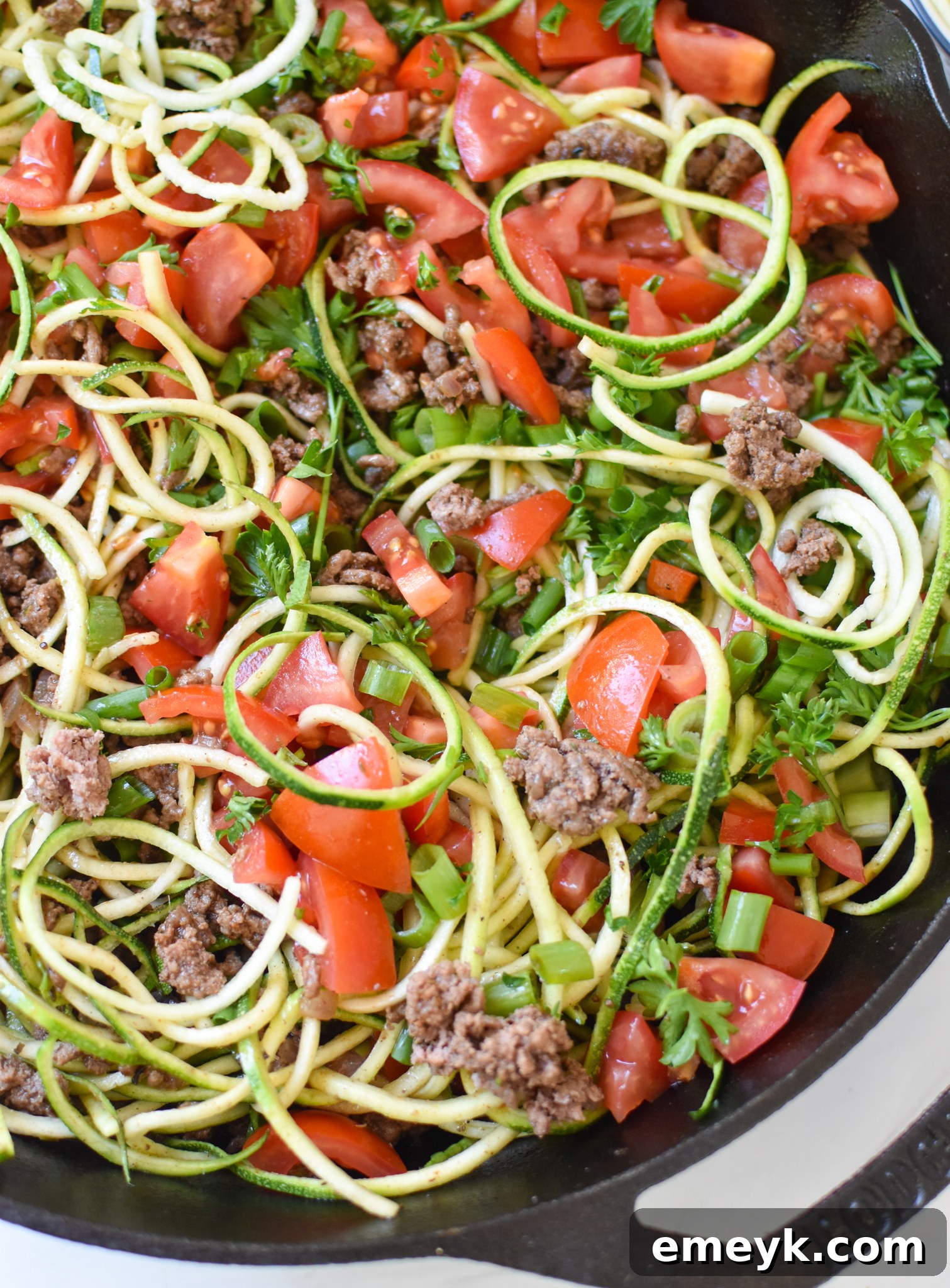 Mediterranean Ground Beef Zucchini Skillet garnished with fresh diced tomatoes and green onions, ready for serving.