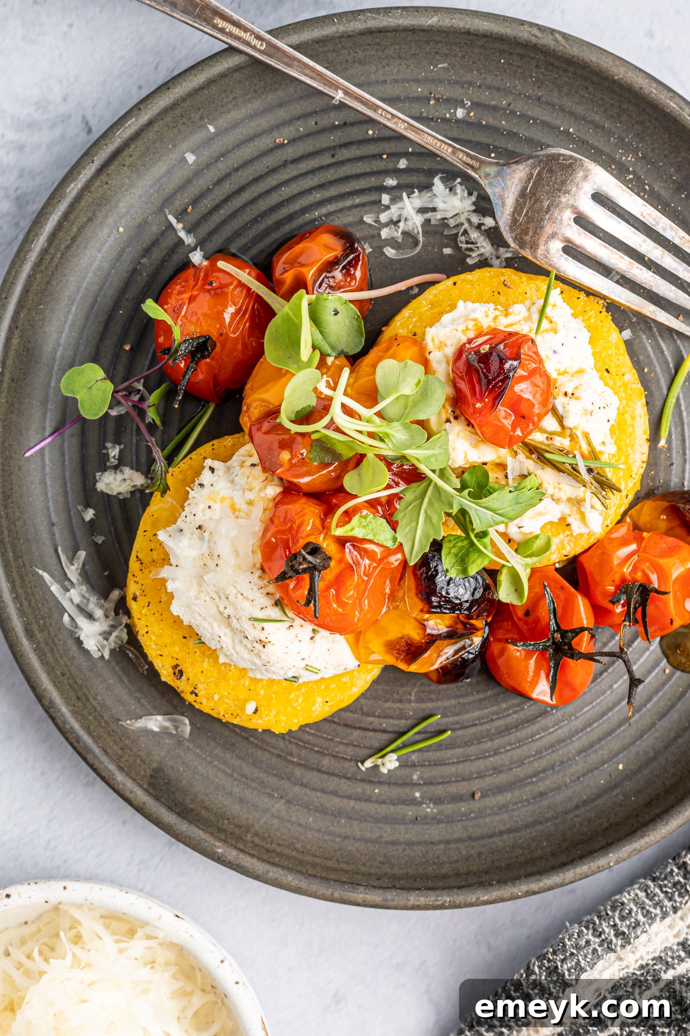 Crispy Polenta Stacks arranged artfully with vibrant roasted cherry tomatoes on top.