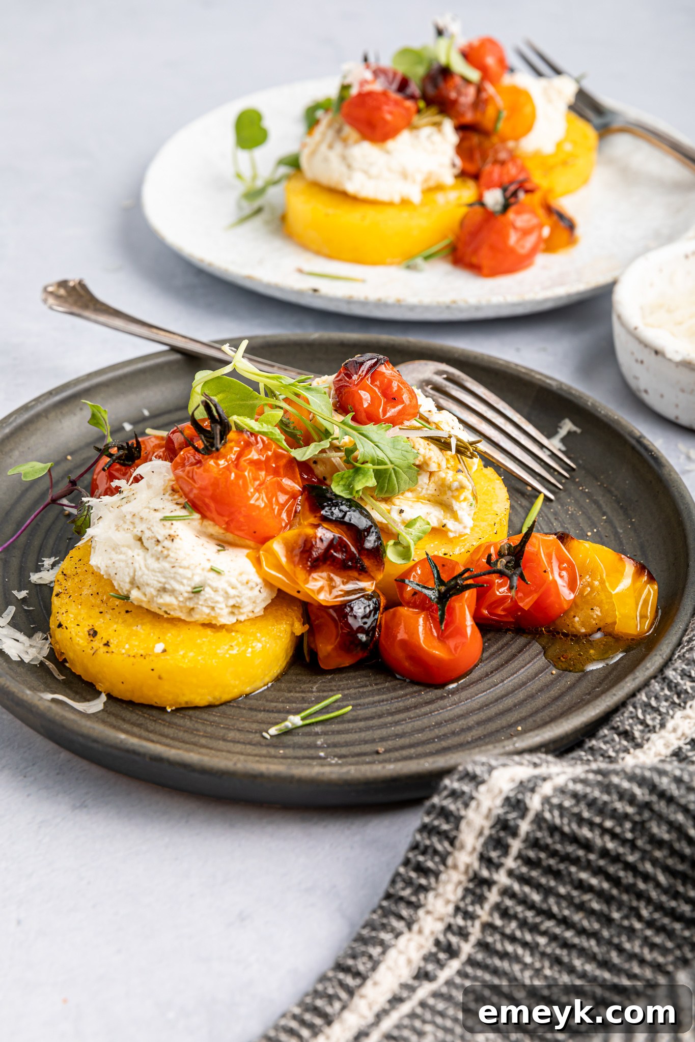 A single Crispy Polenta Stack on a fork, showing the creamy ricotta and roasted tomato topping.