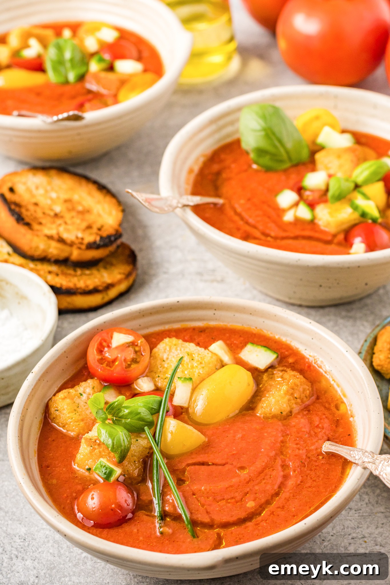 Easy Gazpacho Recipe in a soup bowl, garnished with fresh herbs and diced vegetables.