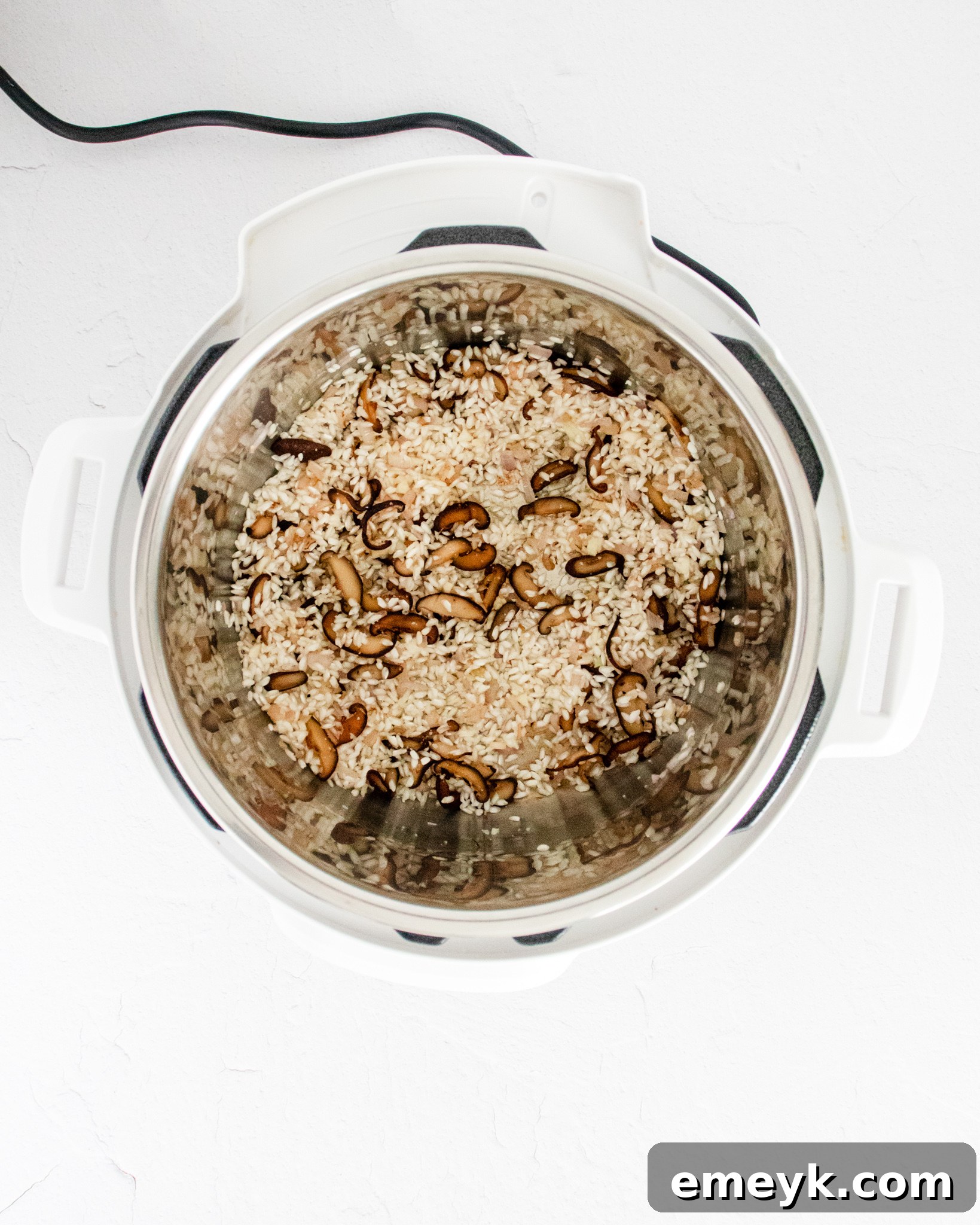 Arborio rice, stock, and other ingredients mixed inside an Instant Pot, ready for pressure cooking.