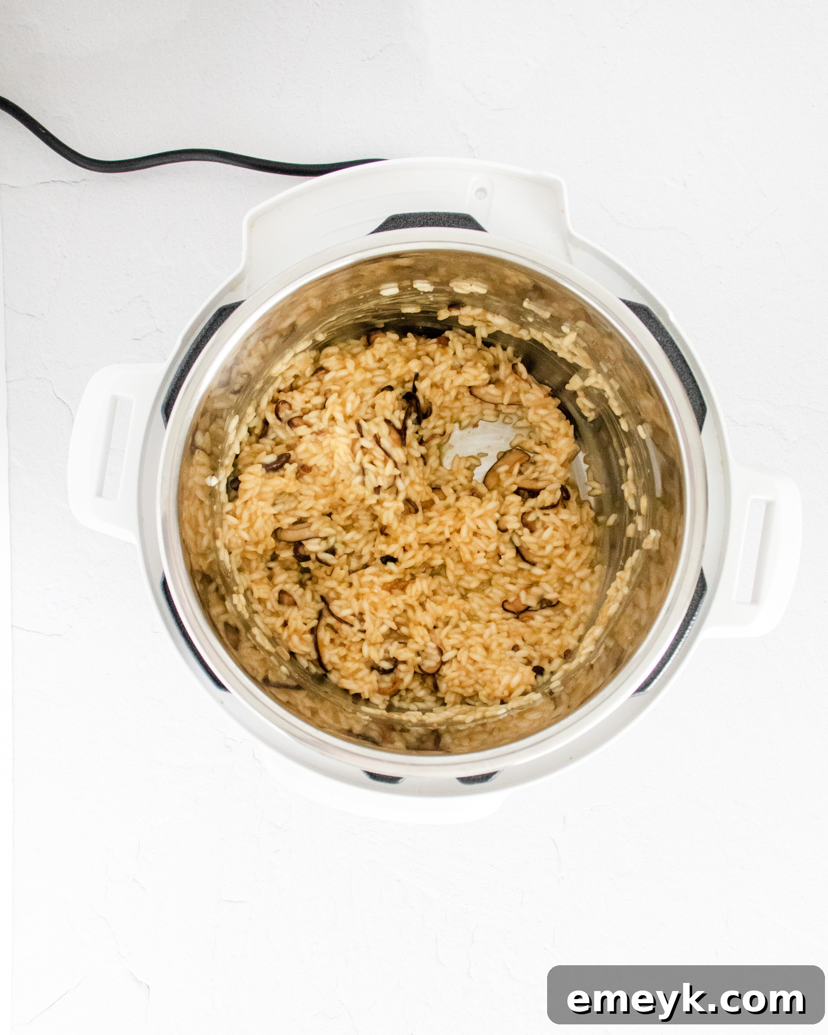 Steam being released from an Instant Pot after cooking, with the risotto inside.