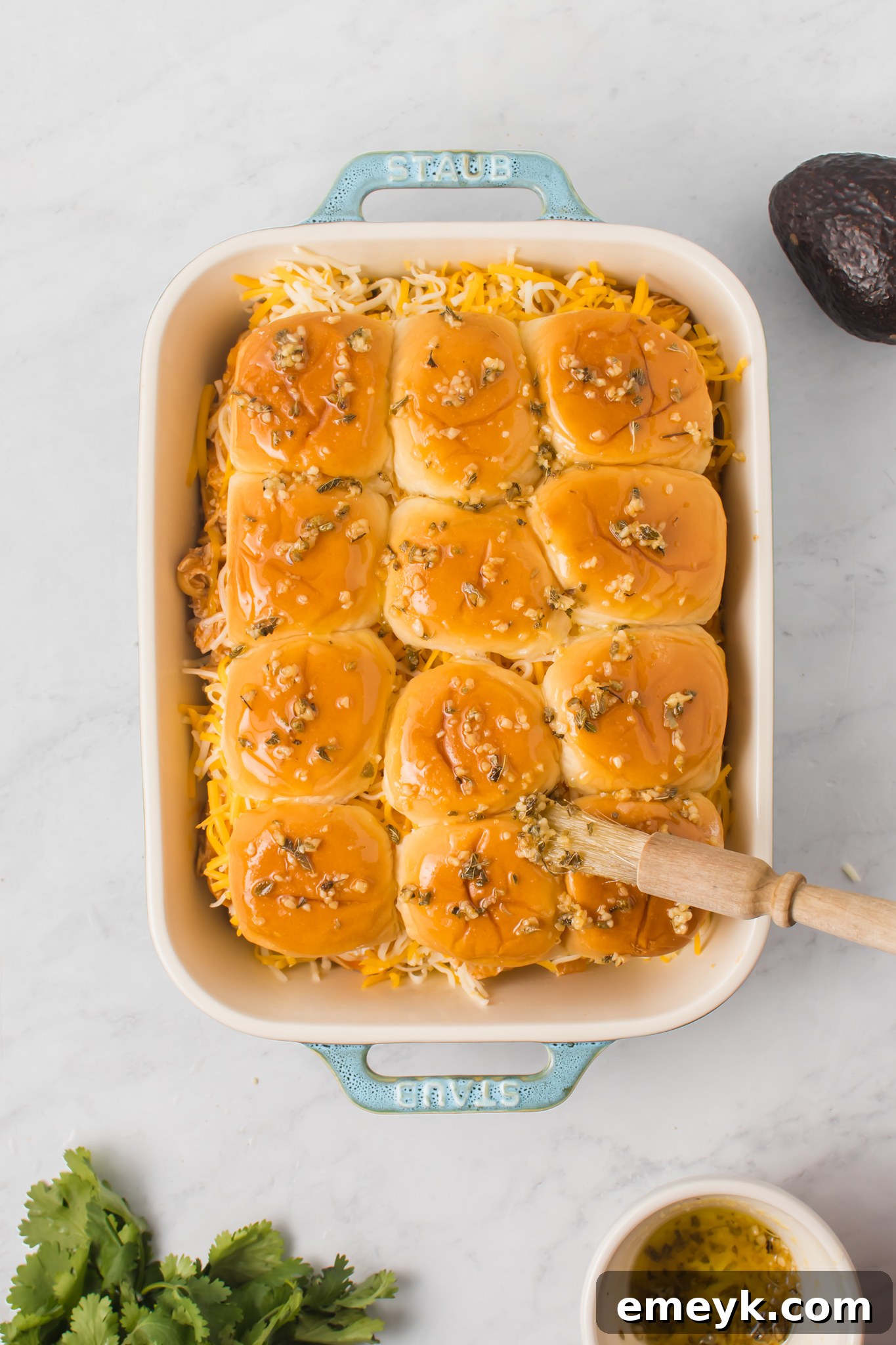 Chicken Enchilada Sliders in a pan, brushed with herb butter and sprinkled with additional herbs.