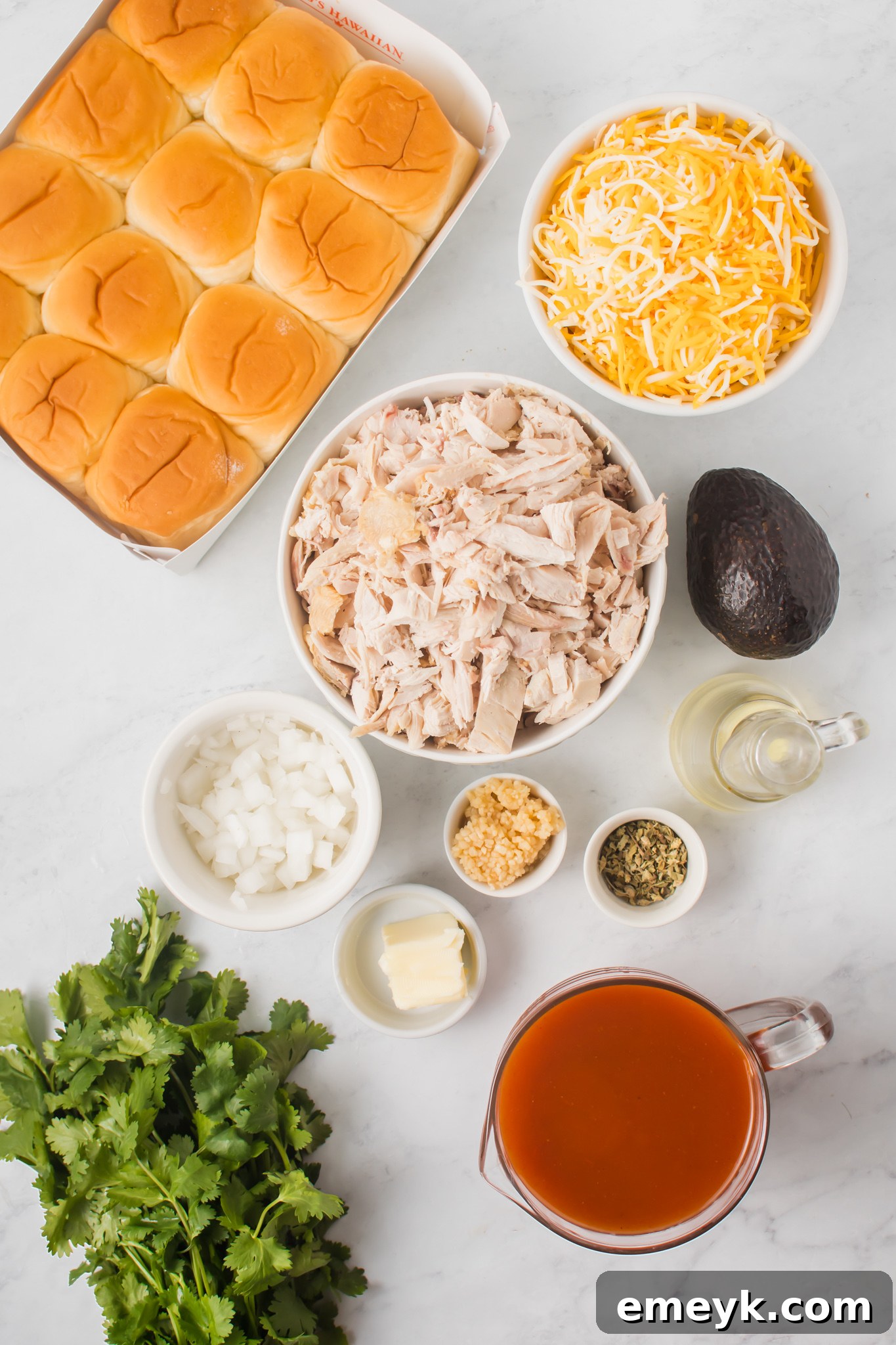 Fresh ingredients laid out for making Chicken Enchilada Sliders, including chicken, enchilada sauce, cheese, and rolls.