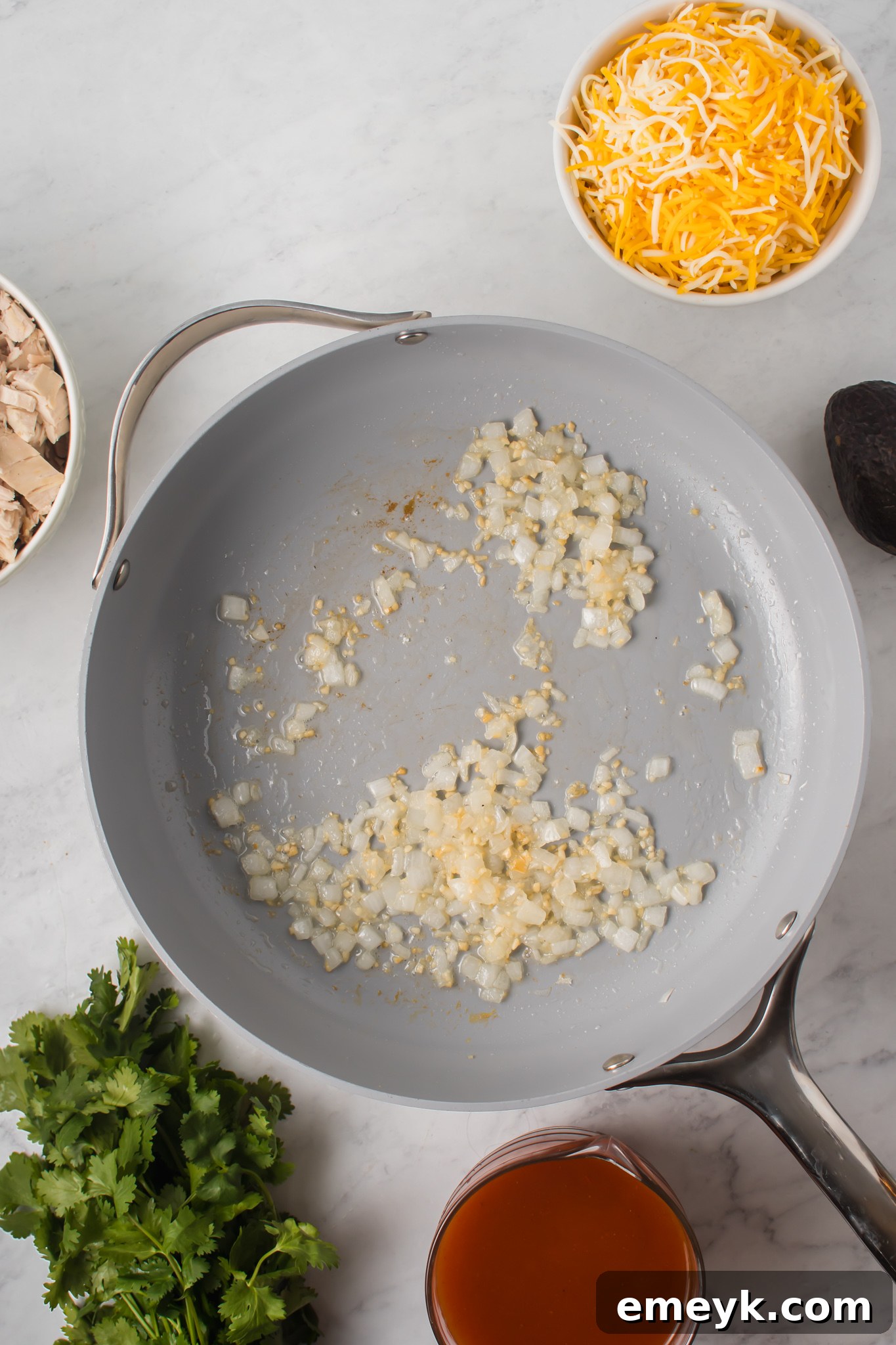 Diced onions being sautéed in a pan with olive oil as the first step for Chicken Enchilada Sliders.