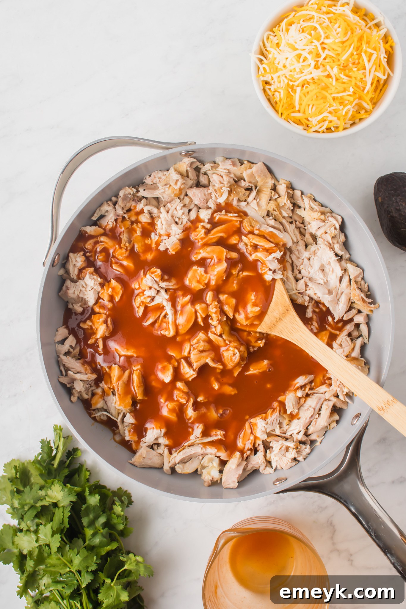 Shredded chicken and enchilada sauce simmering together in a pan for the slider filling.