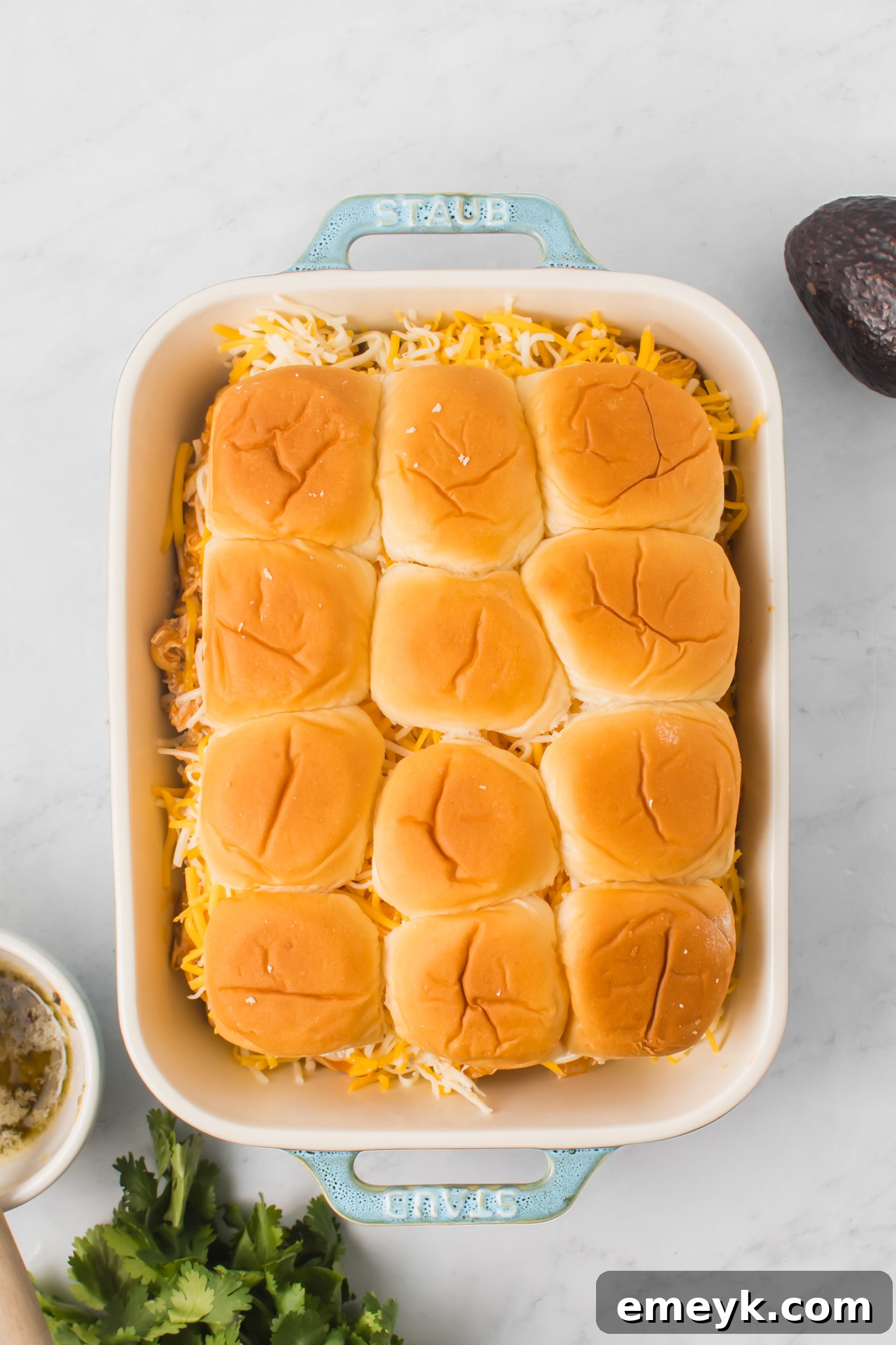 Assembled Chicken Enchilada Sliders in a baking pan, ready for the final topping and baking.