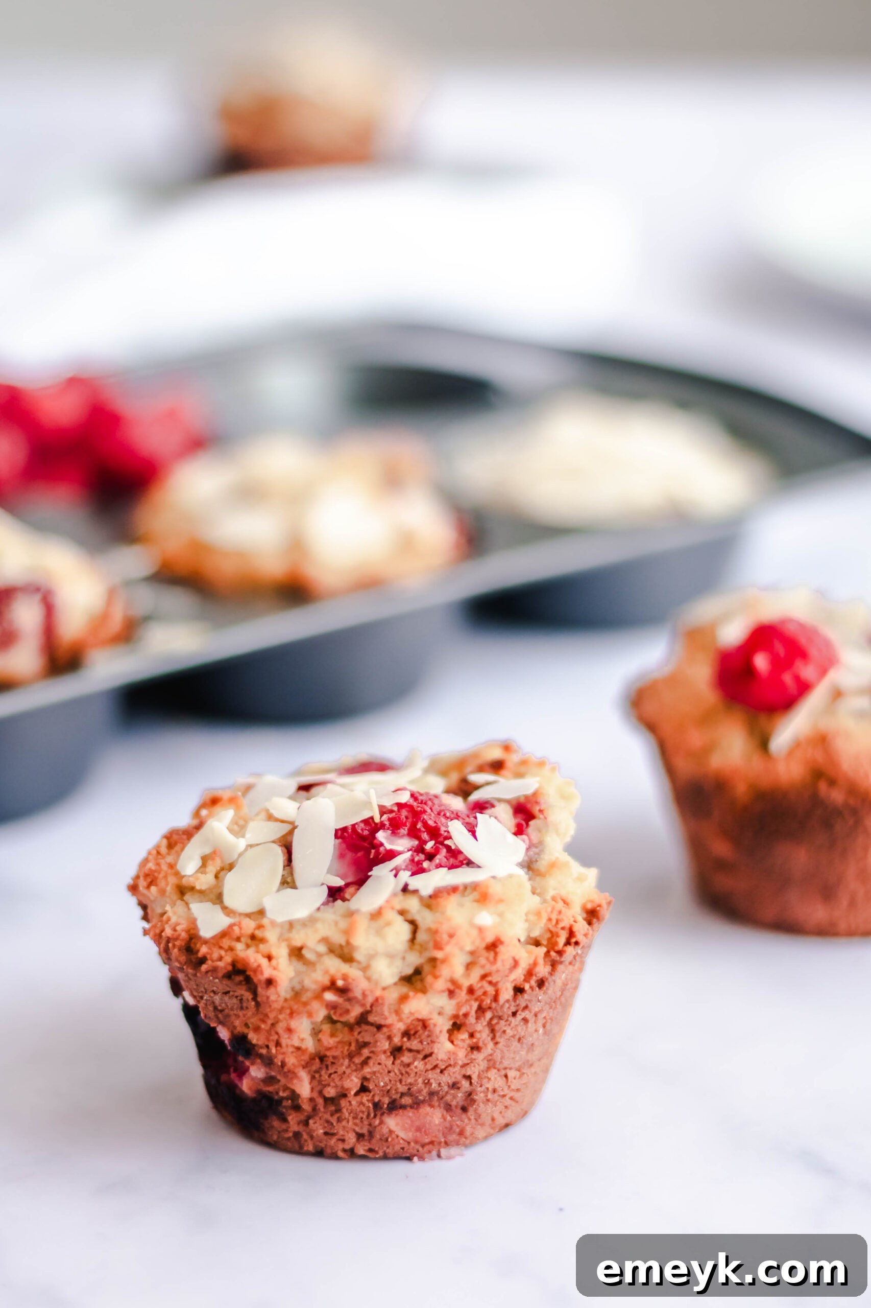 Keto Raspberry Muffins with almonds, garnished with fresh raspberries and lemon slices.