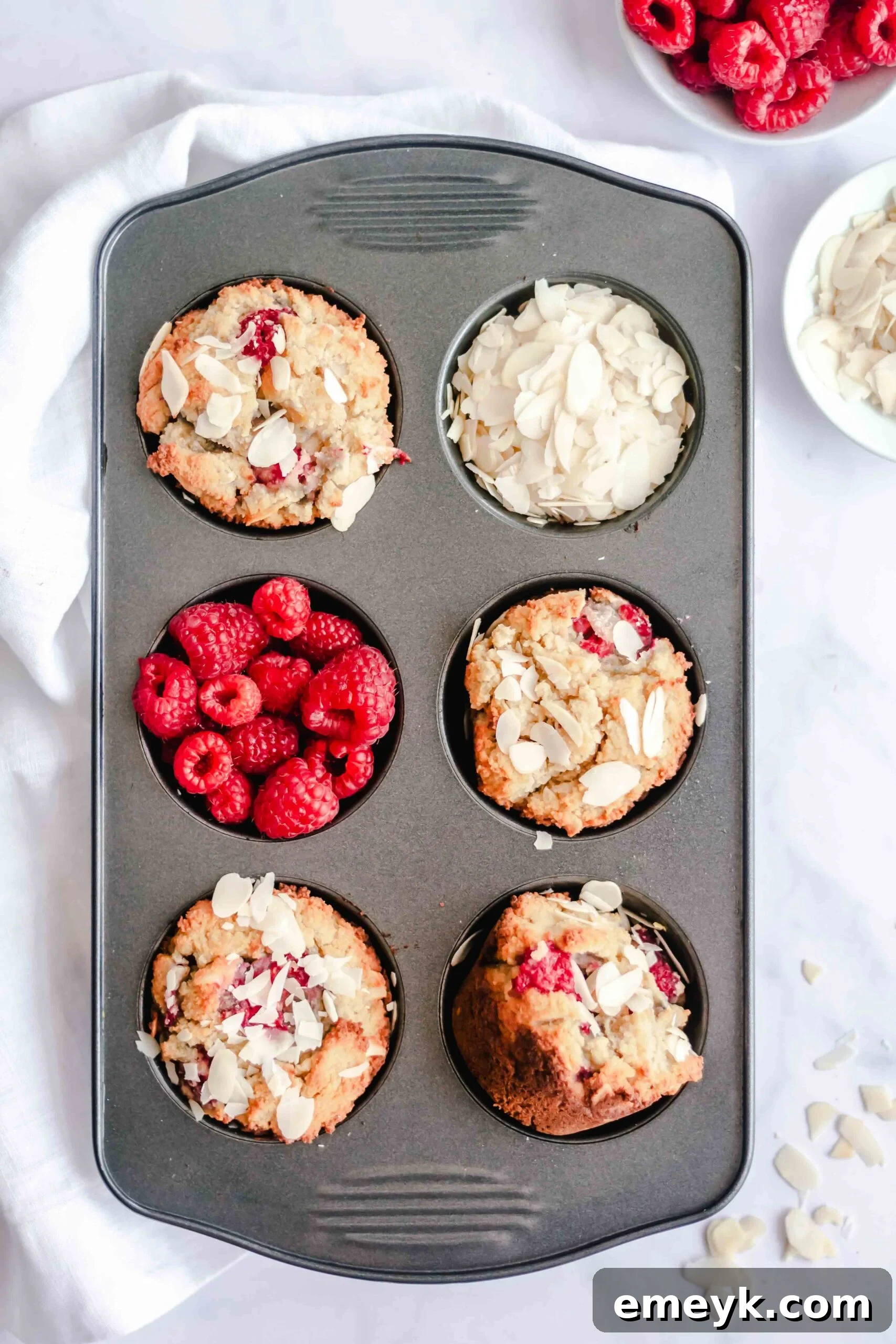 Keto Raspberry Muffins baking in a muffin tin, golden brown and perfectly risen.