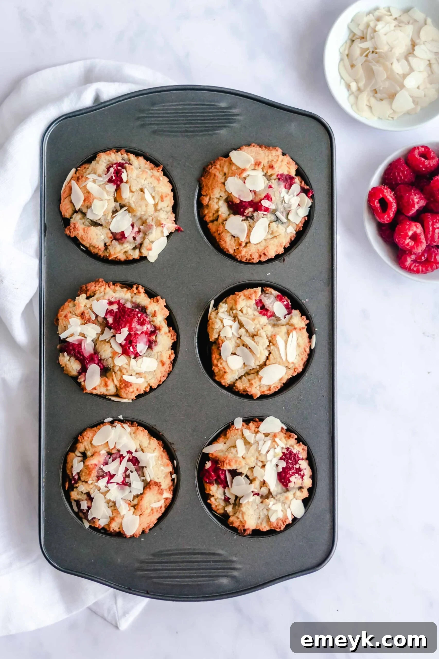 A close-up of a freshly baked Keto Raspberry Muffin, revealing its soft interior and vibrant raspberries.