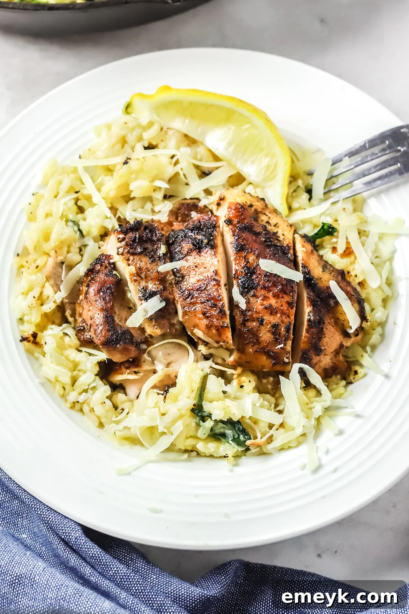 A serving of Oven Baked Chicken Thighs with Risotto, garnished with fresh herbs and a fork resting beside it, highlighting the creamy texture.