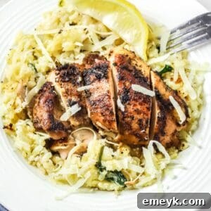 A top-down view of Oven Baked Chicken Thighs with Risotto, garnished with fresh herbs and a drizzle of olive oil.
