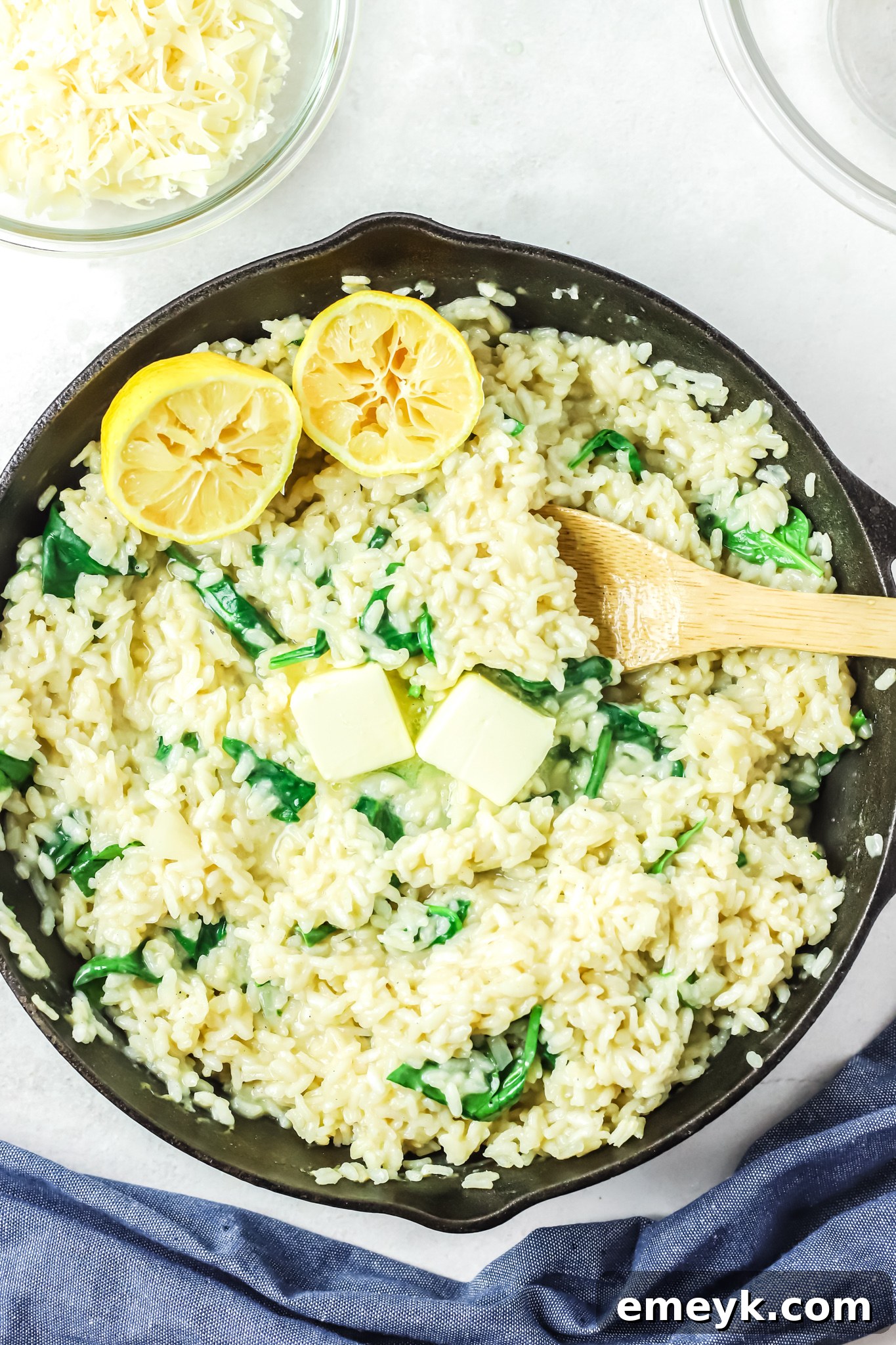 Oven Baked Chicken Thighs with Risotto, served in the skillet with lemon wedges and fresh parsley, ready to be enjoyed.
