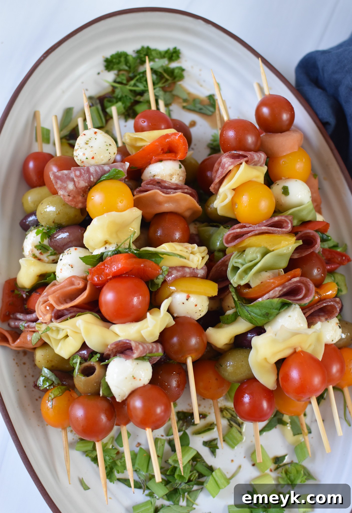 Antipasto Picks 5 Antipasto Skewers presented attractively on a white serving platter, garnished with fresh herbs.